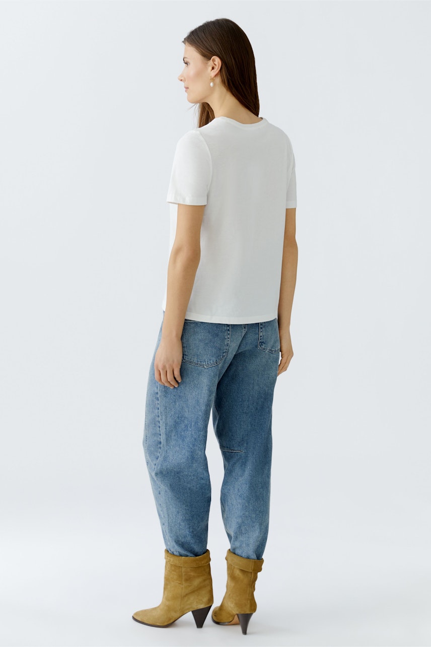 Casual women's T-shirt: A woman in a white T-shirt paired with relaxed-fit jeans and stylish boots.