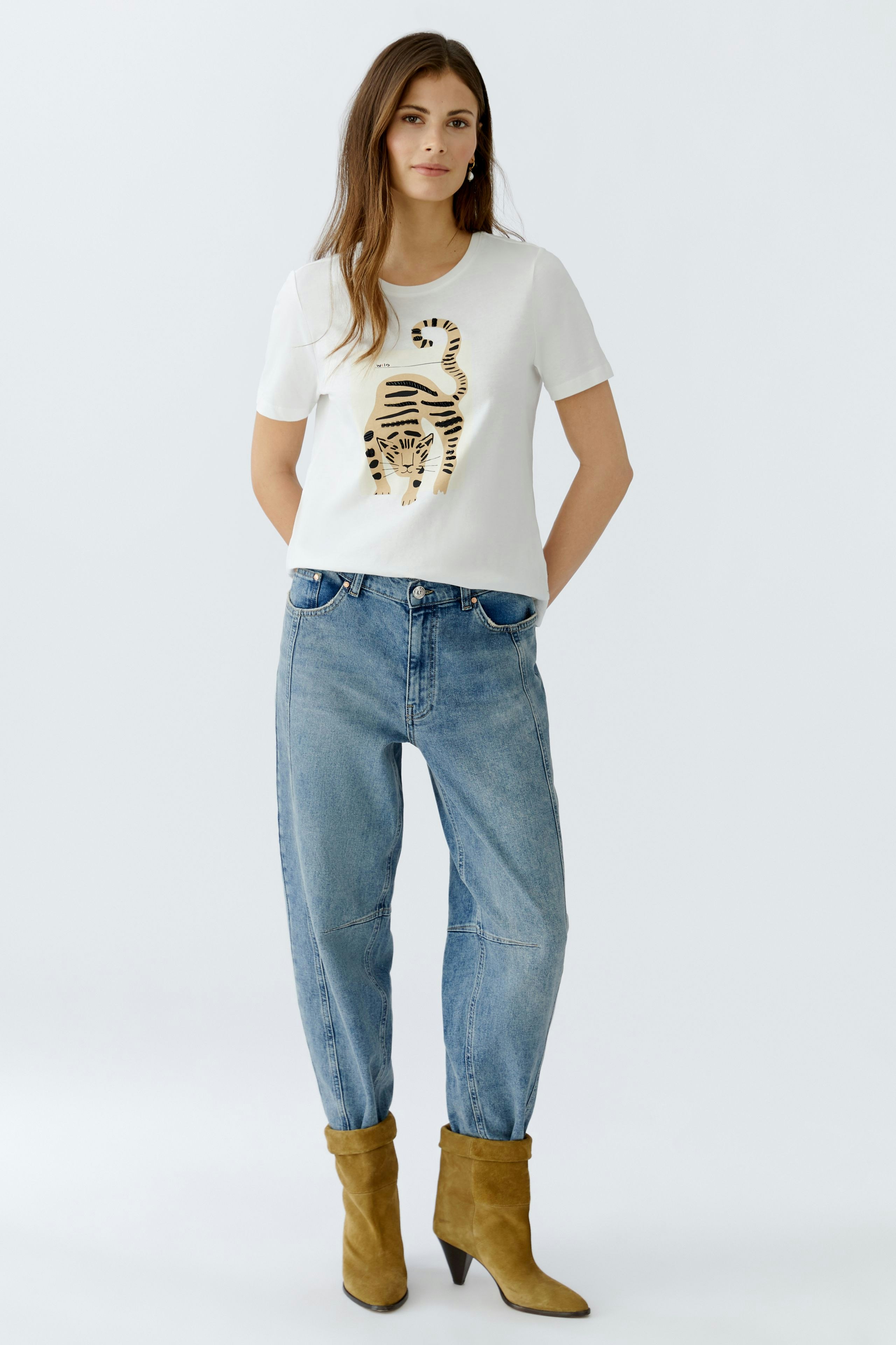 Casual women's T-shirt: A woman in a white tee featuring a tiger print, paired with relaxed jeans.