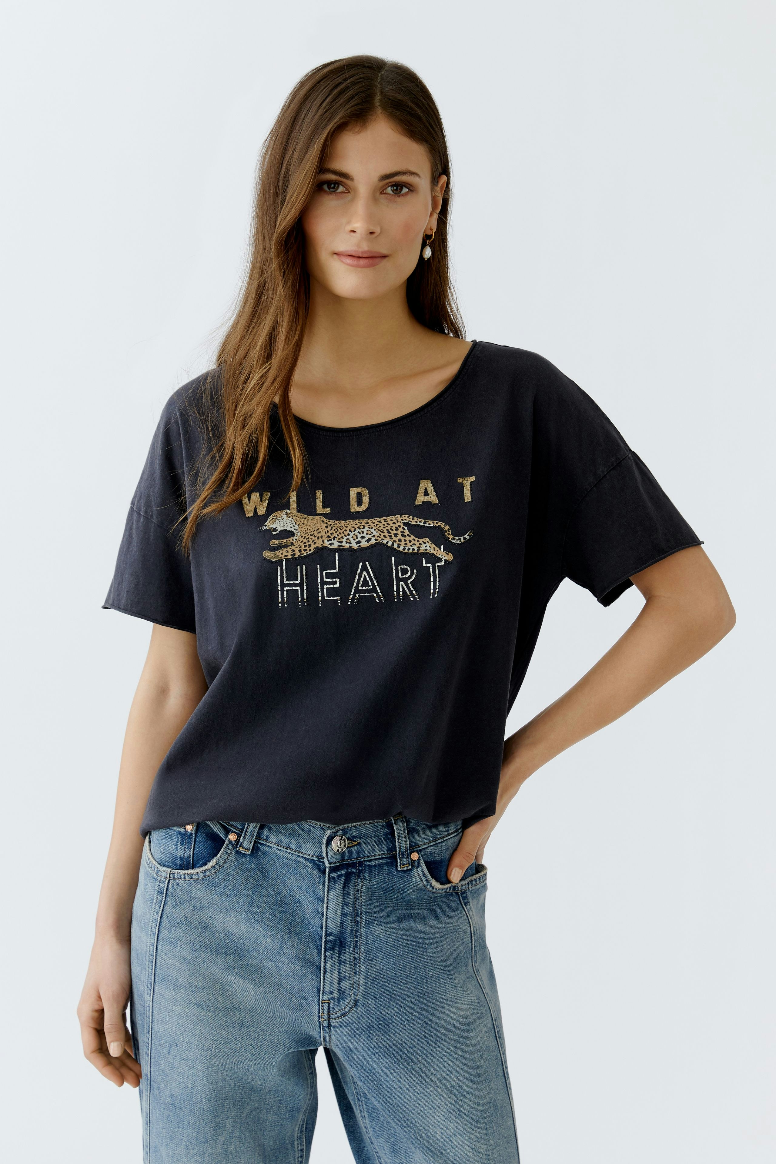 Casual women's T-shirt: Woman in a black tee with a leopard print and 'WILD AT HEART' text.