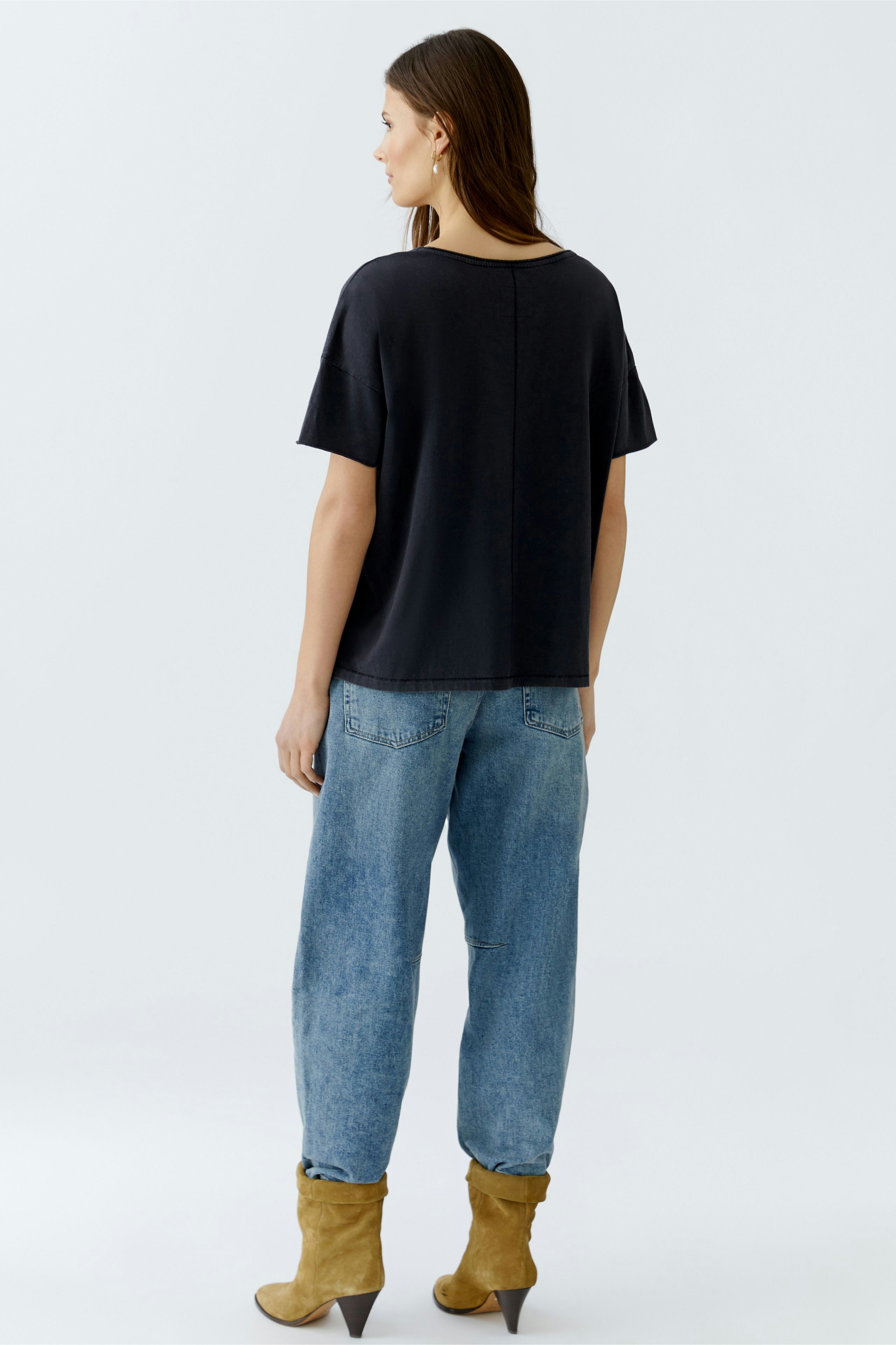 Casual women's T-shirt: Woman in a black T-shirt paired with relaxed-fit jeans.