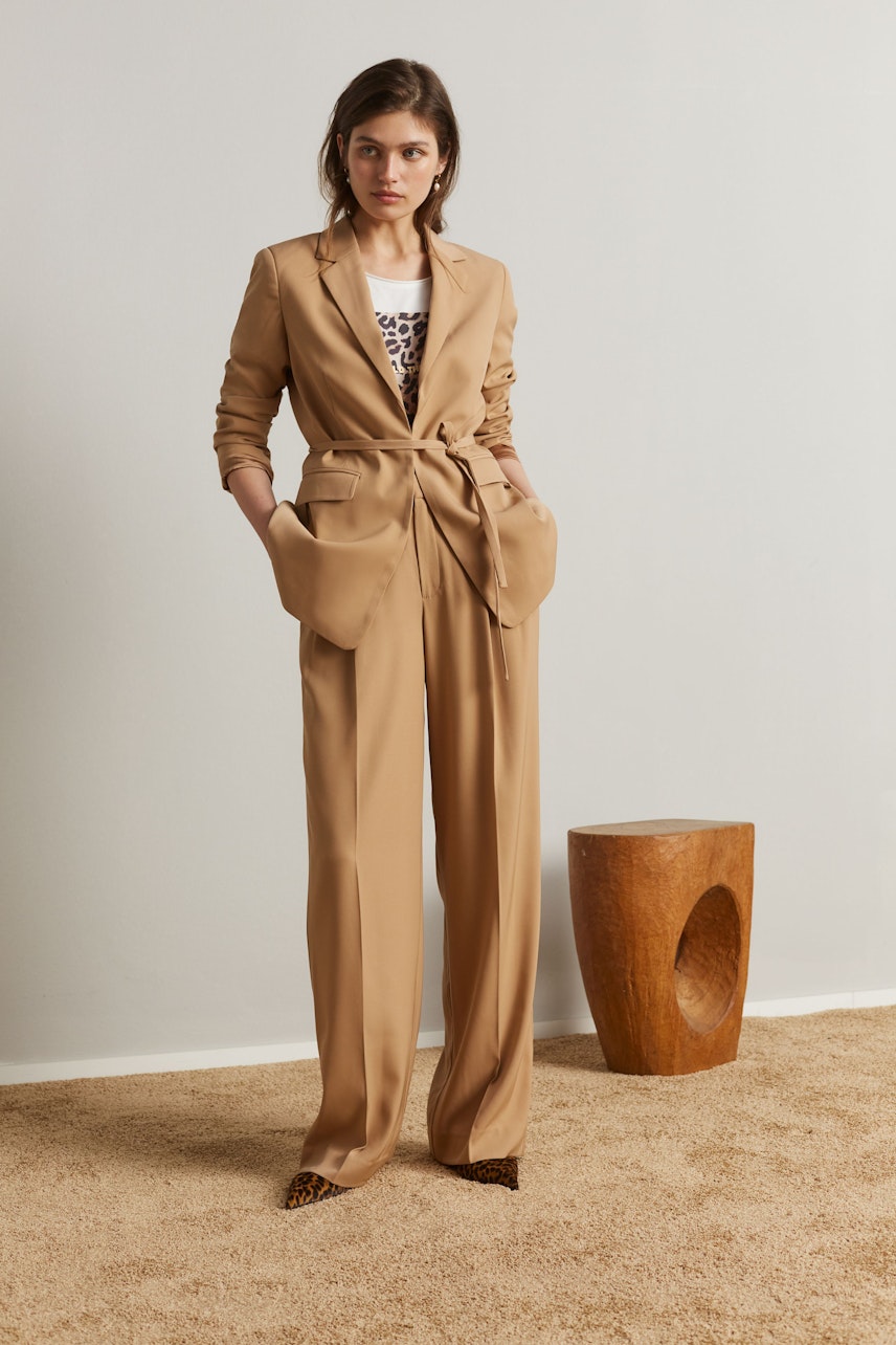 Stylish women's T-shirt: A woman in a beige blazer over a printed tee, exuding confidence.
