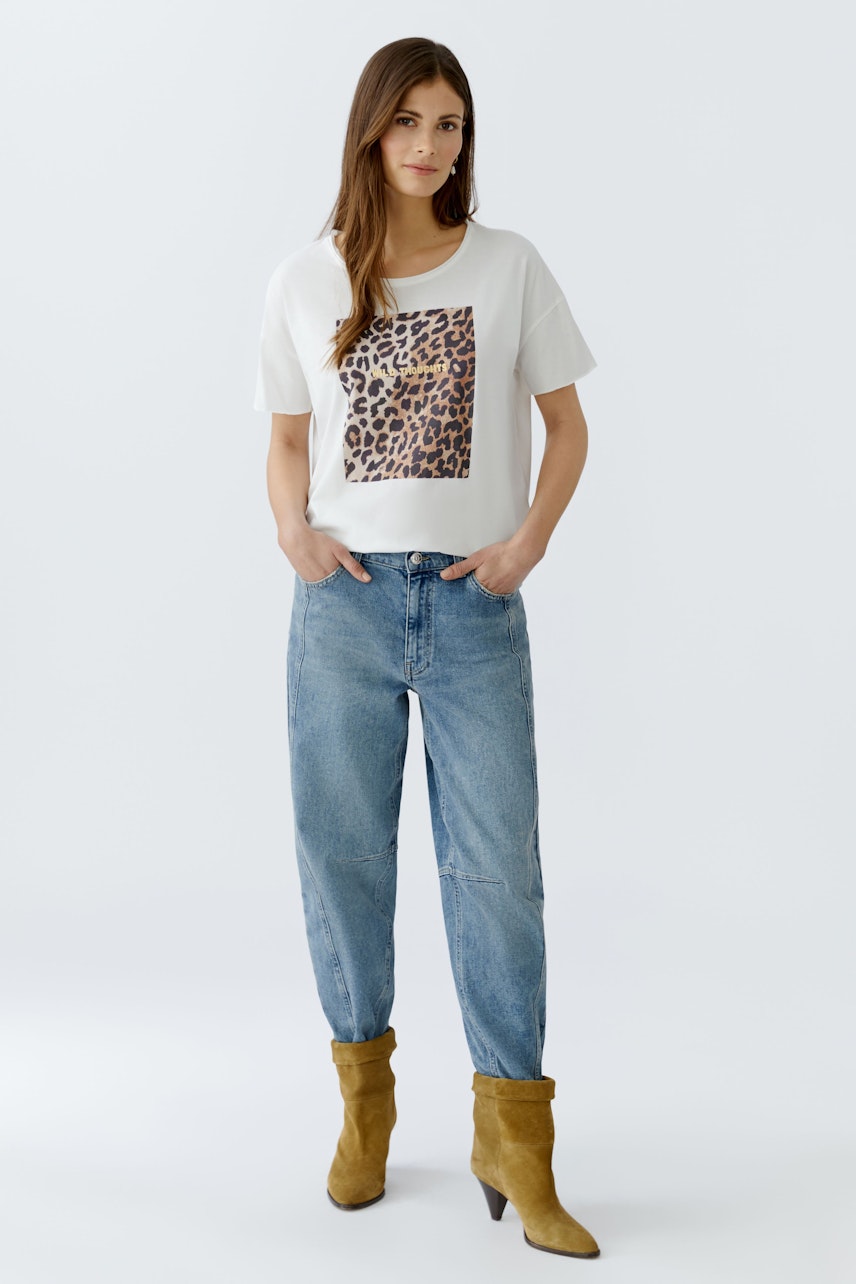 Casual women's T-shirt: Young woman in a white tee with a leopard print design, paired with relaxed jeans.
