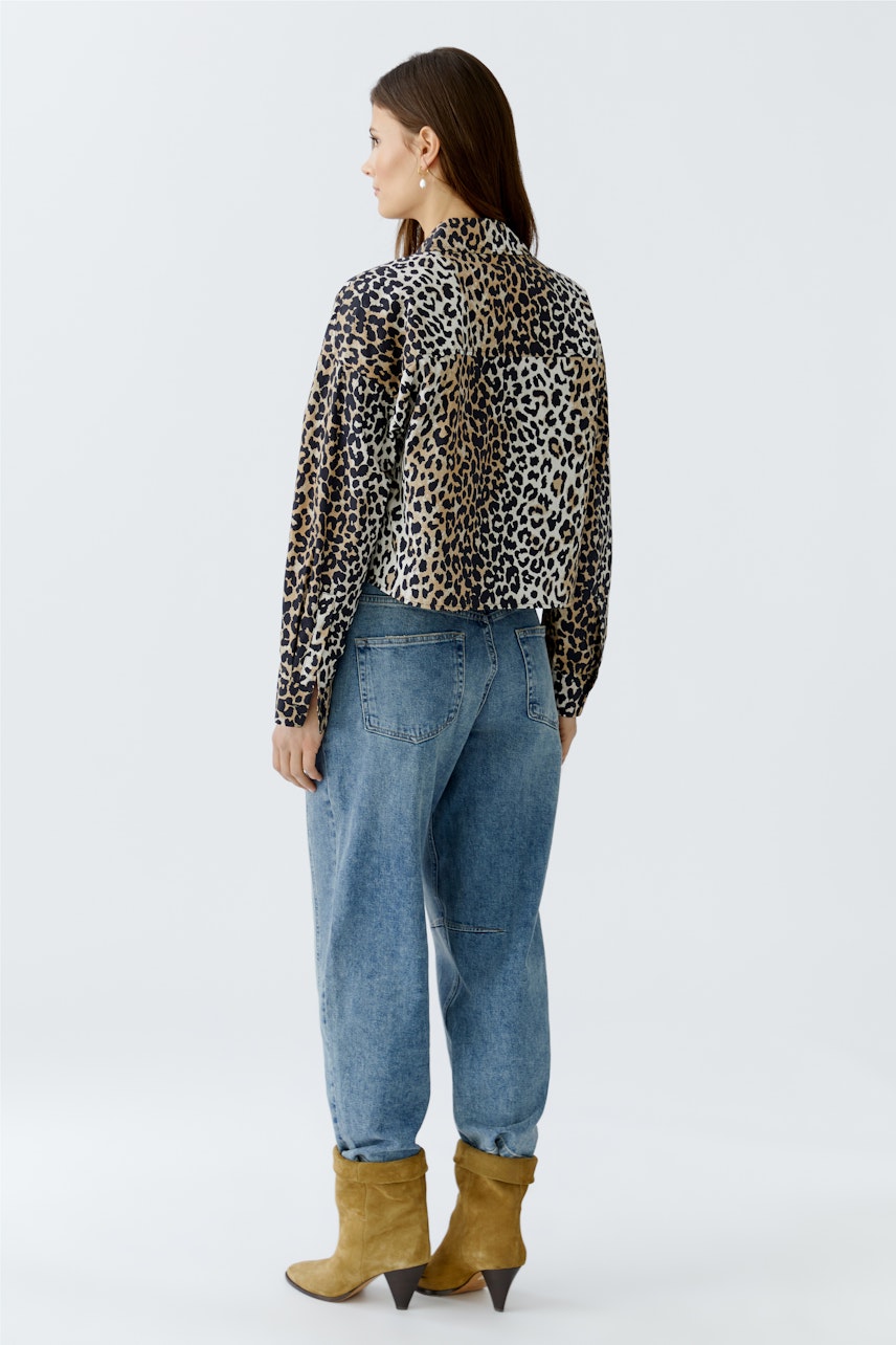 Stylish women's blouse: A woman in a leopard print blouse paired with relaxed jeans.