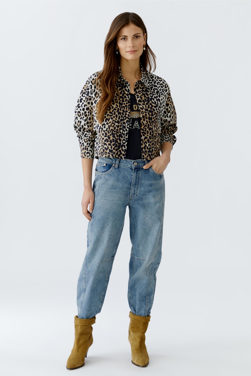 Casual women's blouse: A woman in a leopard print blouse and relaxed jeans poses confidently.