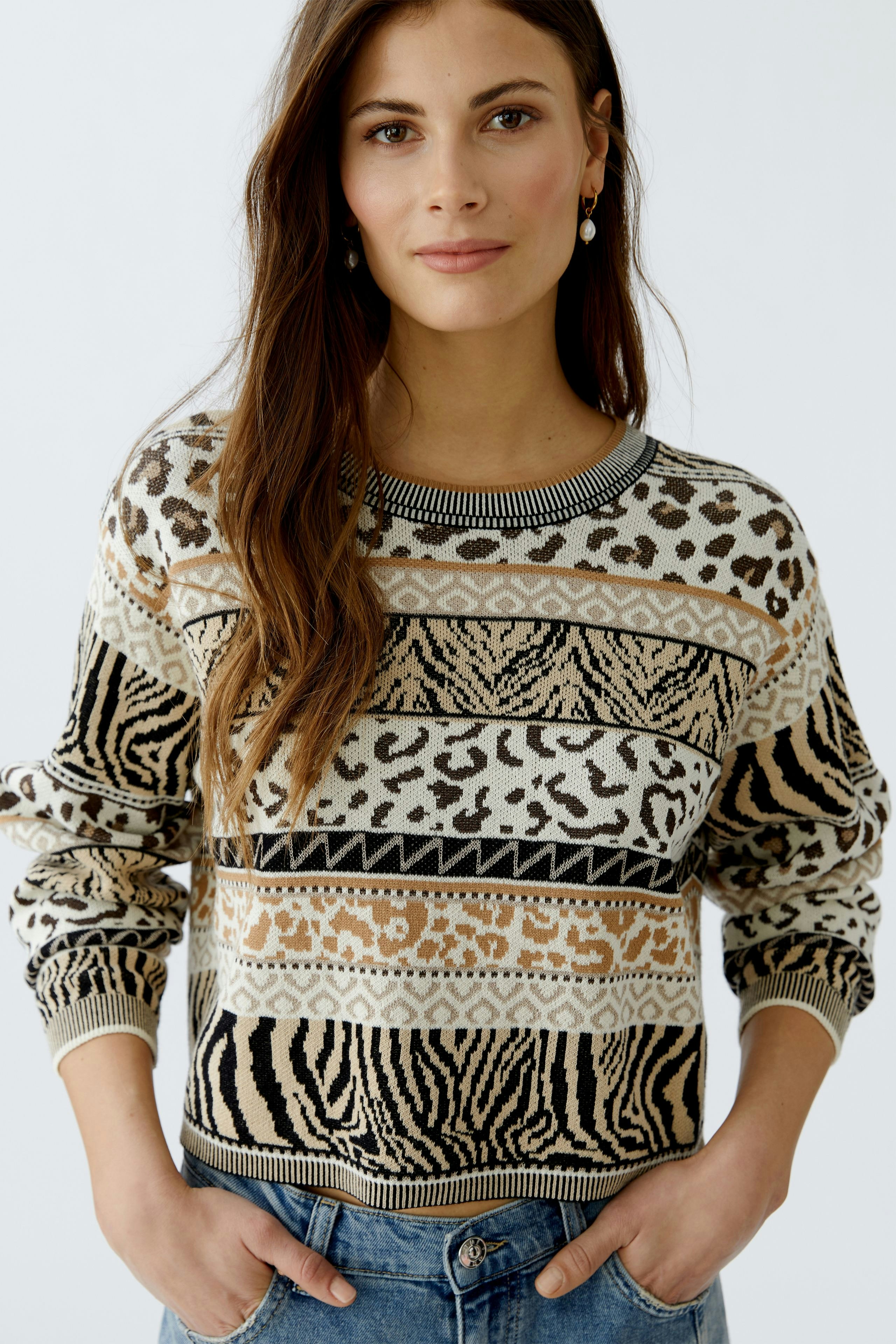 Damen-Pullover: Frau trägt einen gemusterten Pullover mit Tiermotiven und lässigem Schnitt.
