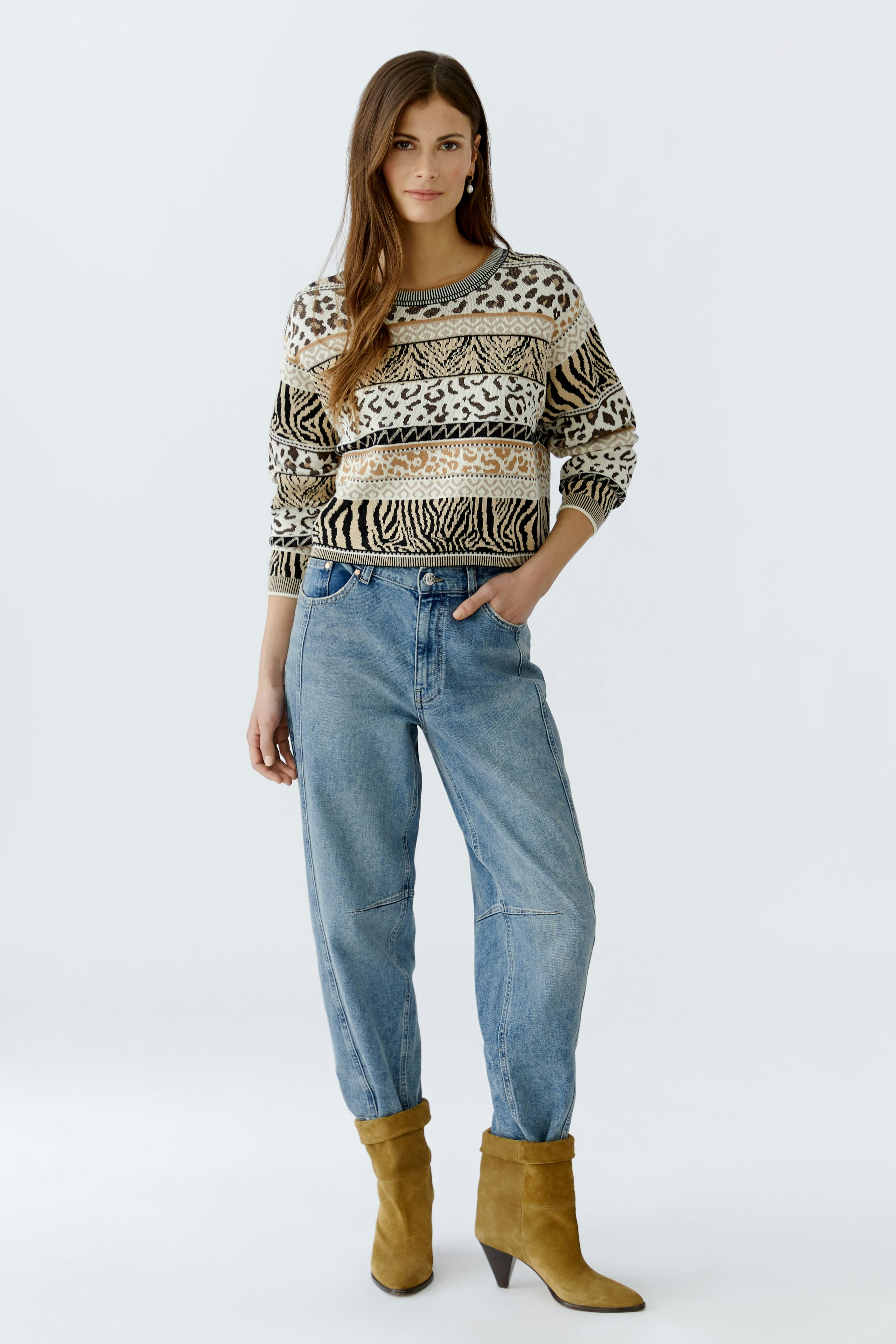 Damen-Pullover: Frau in gemustertem Strickpullover mit lässigen Jeans und Stiefeln.