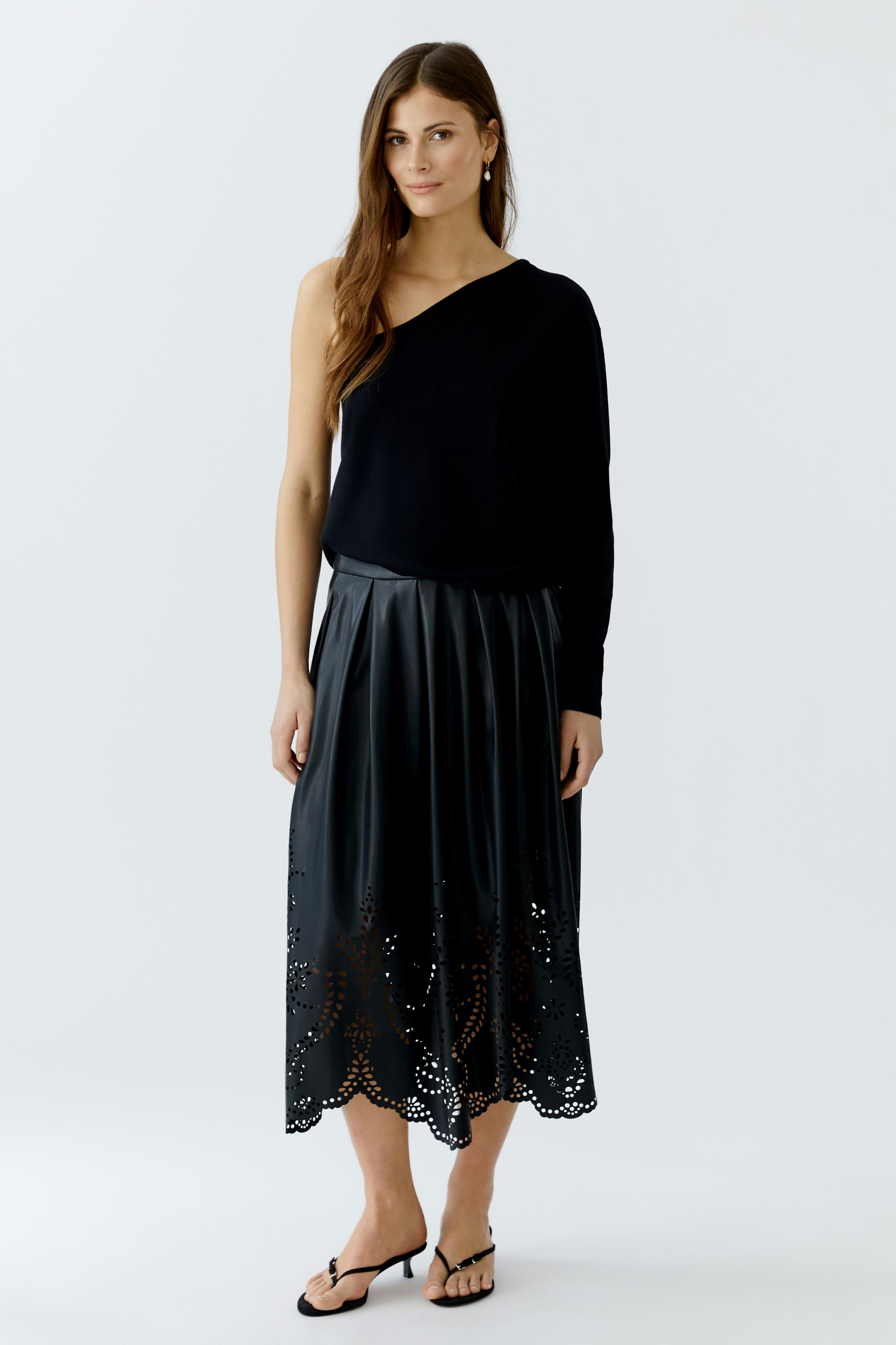 Damen-Pullover: Frau in schwarzem, einseitig geschnittenem Pullover mit lässigem Look.