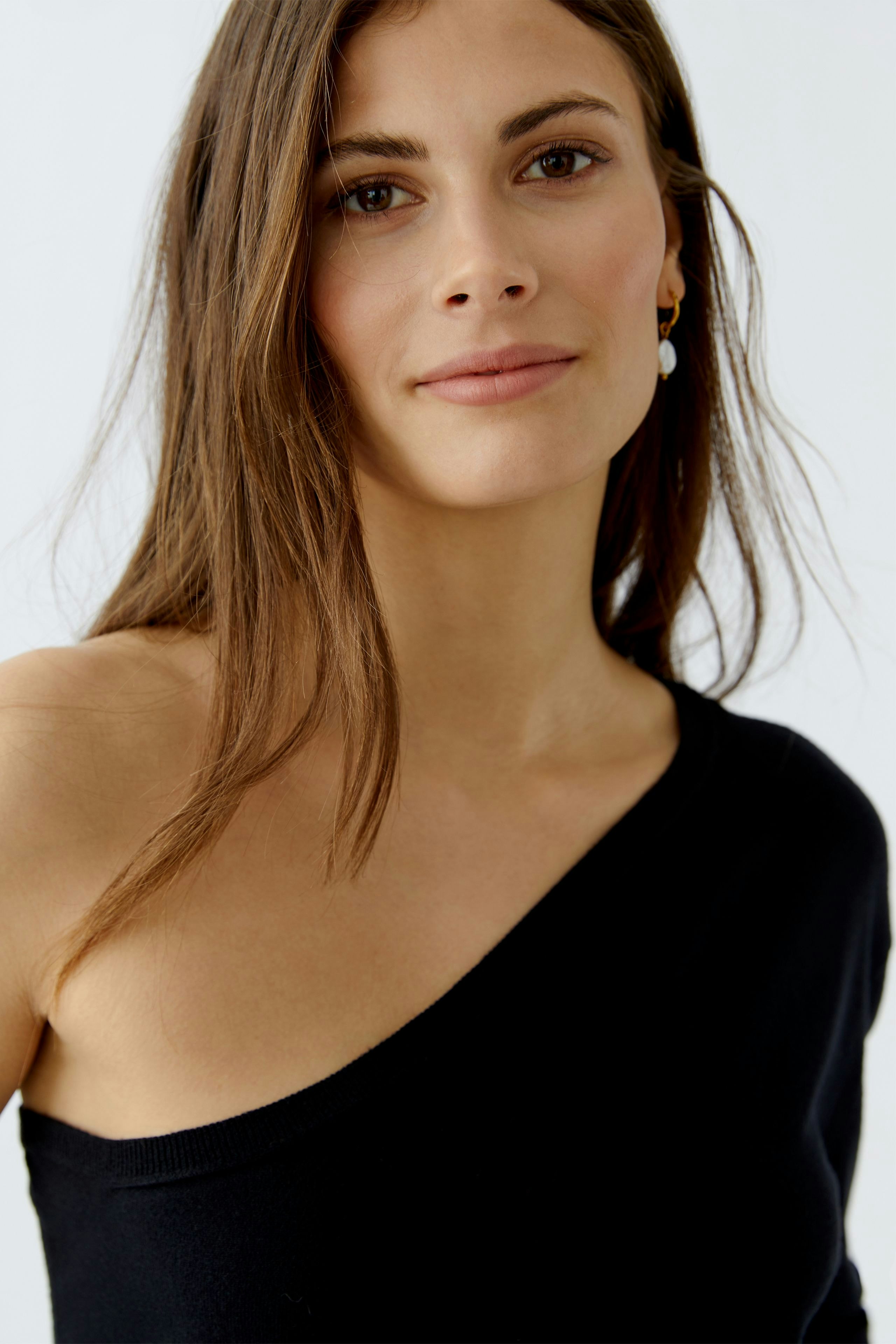 Damen-Pullover: Junge Frau in schwarzem, einseitig geschnittenem Pullover mit lässigem Look.