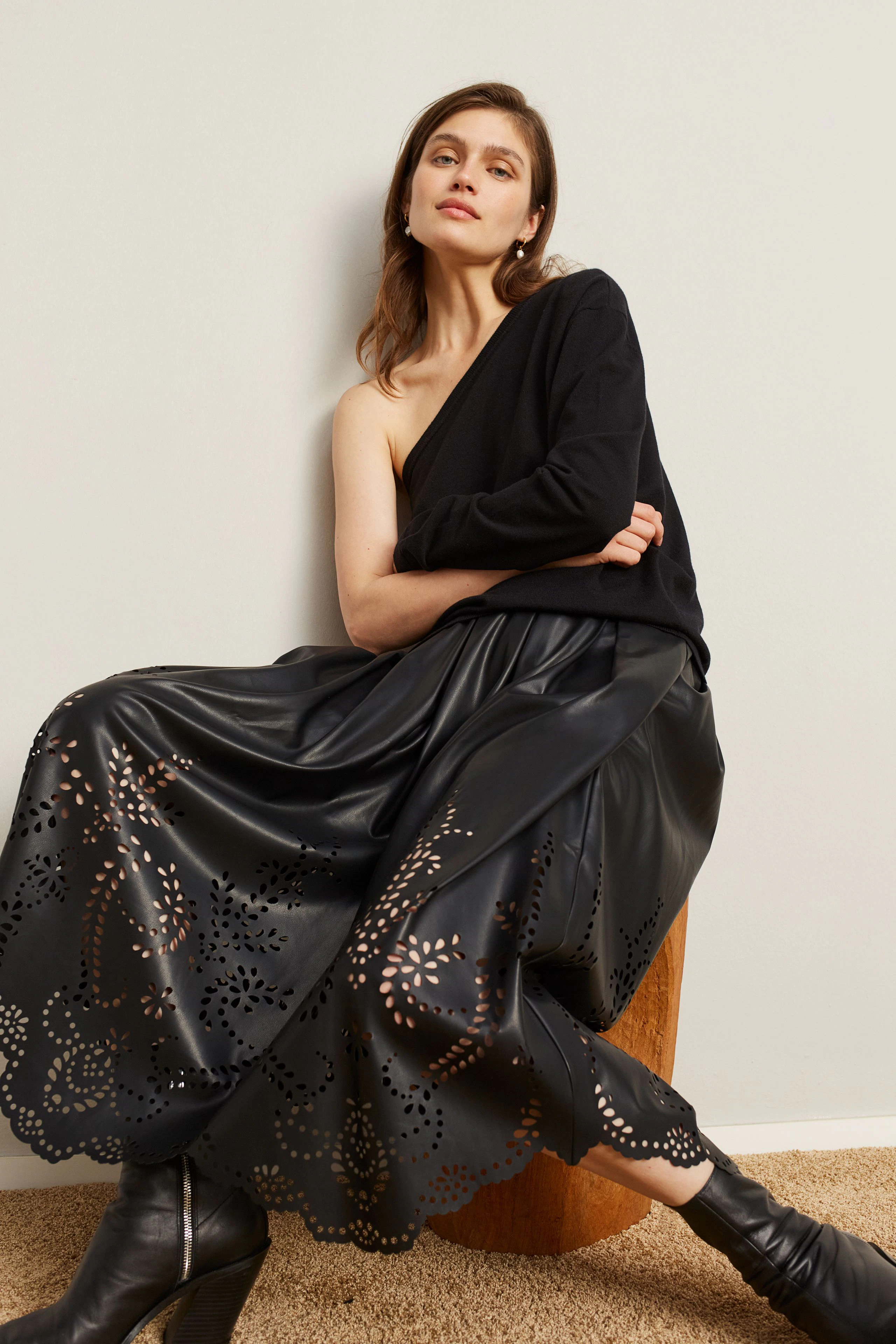 Casual women's pullover: Woman in a black pullover paired with a stylish skirt, sitting confidently.