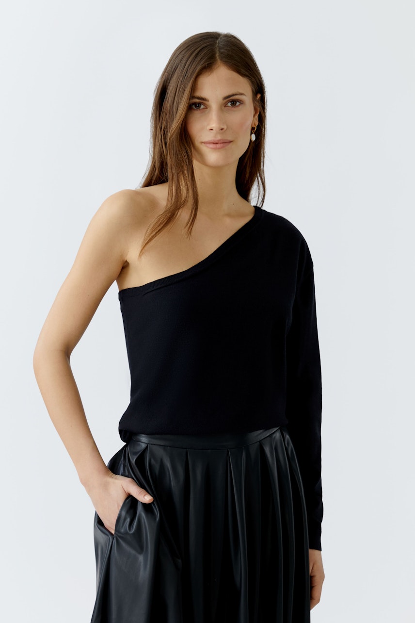 Modern women's pullover: A woman in a black one-shoulder pullover paired with a pleated skirt.