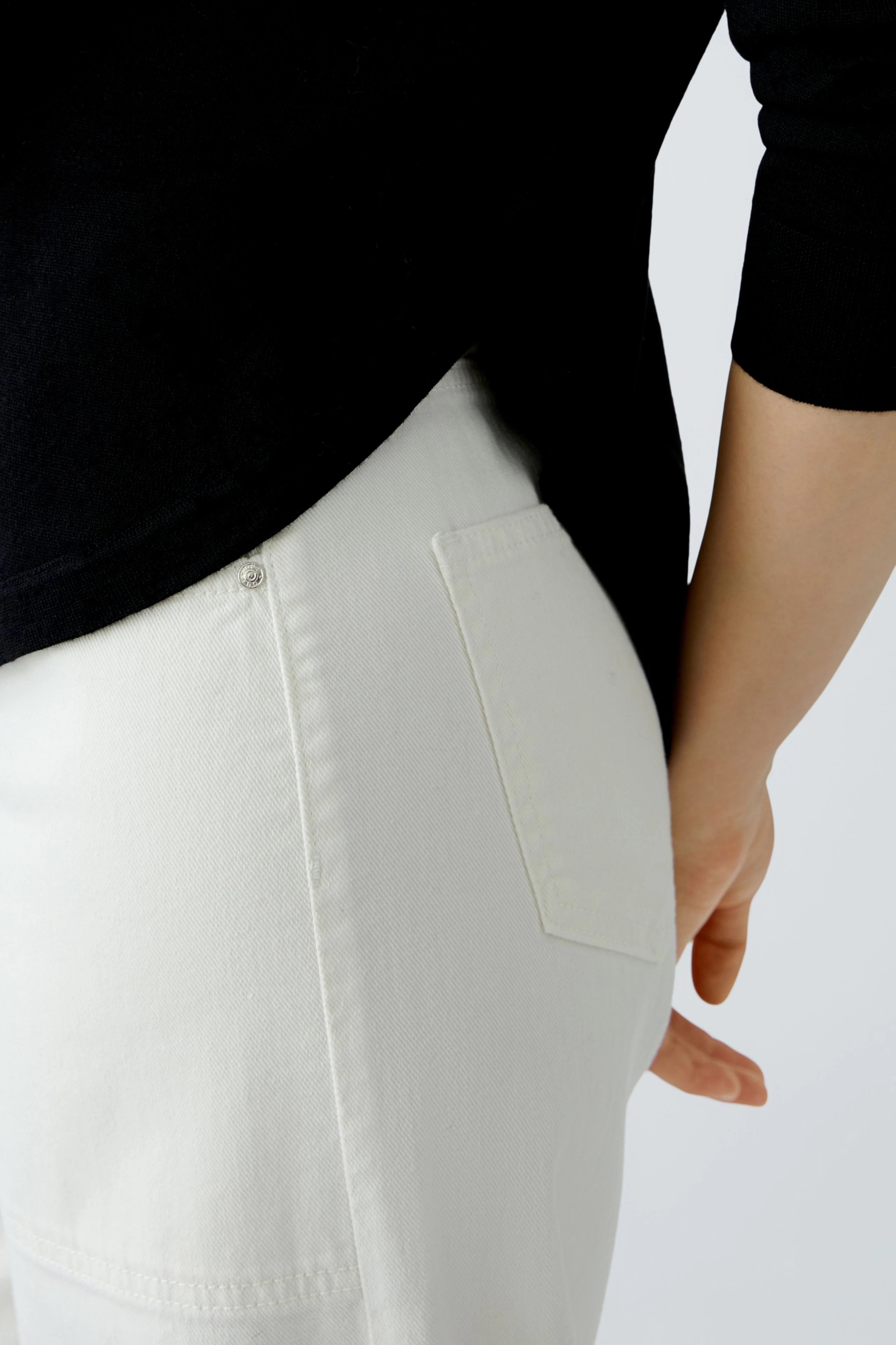 Damen-Pullover: Frau trägt einen schwarzen Pullover, kombiniert mit hellen Jeans, lässiger Look.