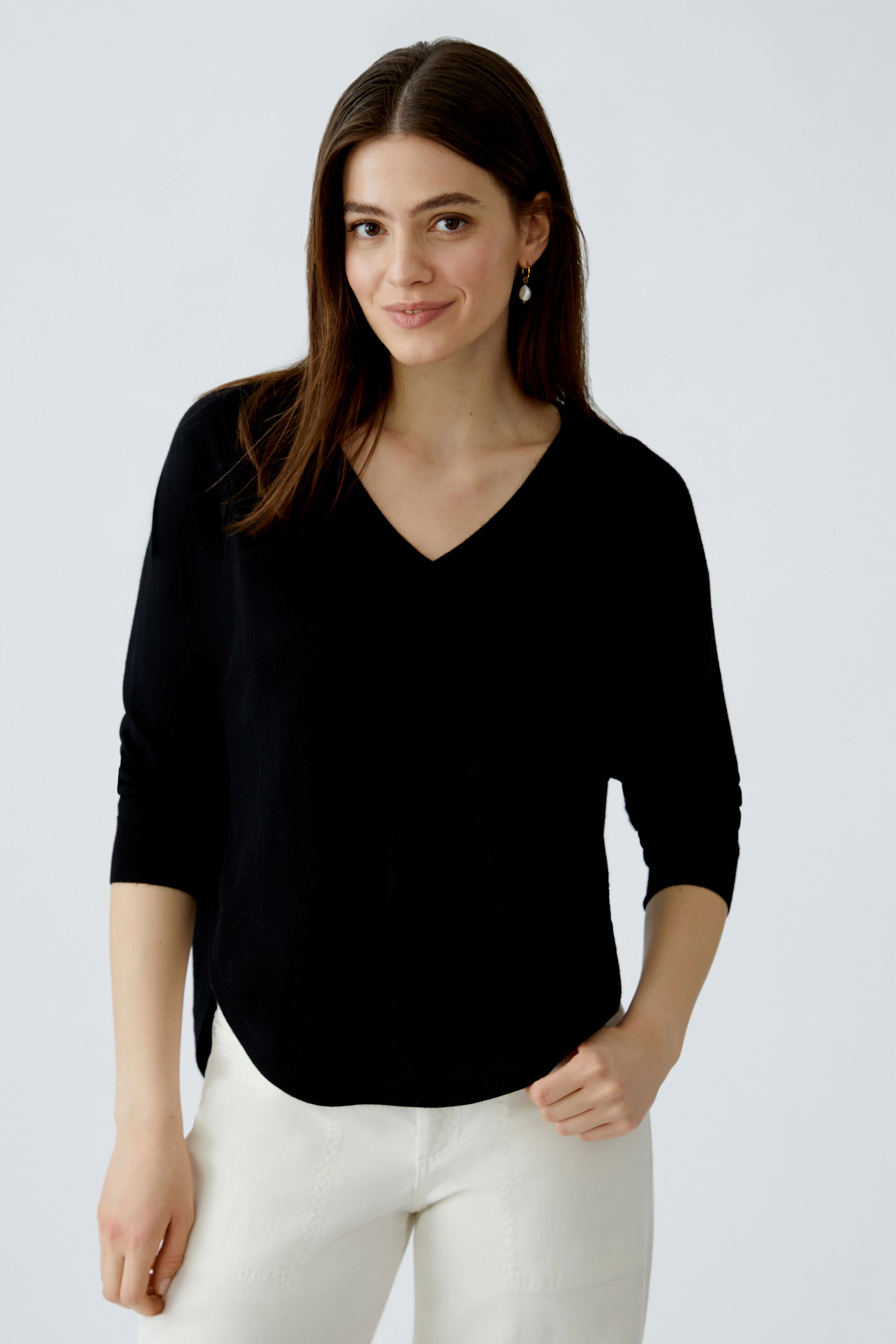 Damen-Pullover: Frau in schwarzem, lässigem Pullover mit V-Ausschnitt und 3/4-Ärmeln lächelt freundlich.