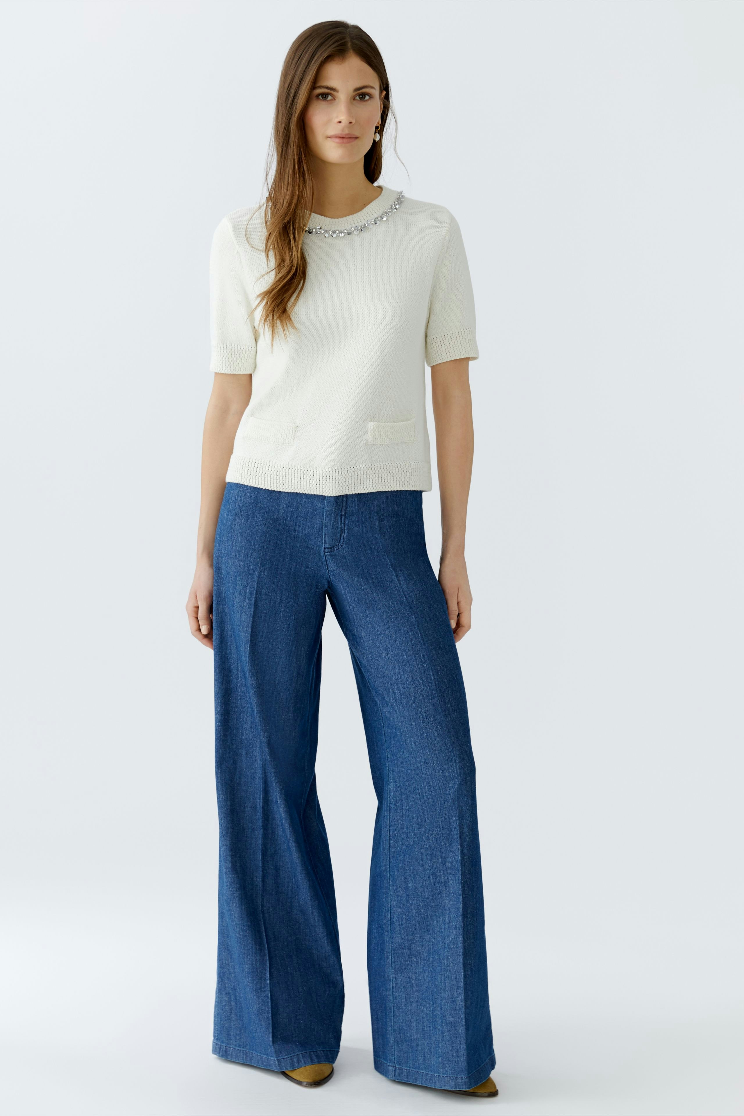 Damen-Pullover: Frau in hellem Pullover mit Rundhalsausschnitt und kurzen Ärmeln, kombiniert mit weiten Jeans.