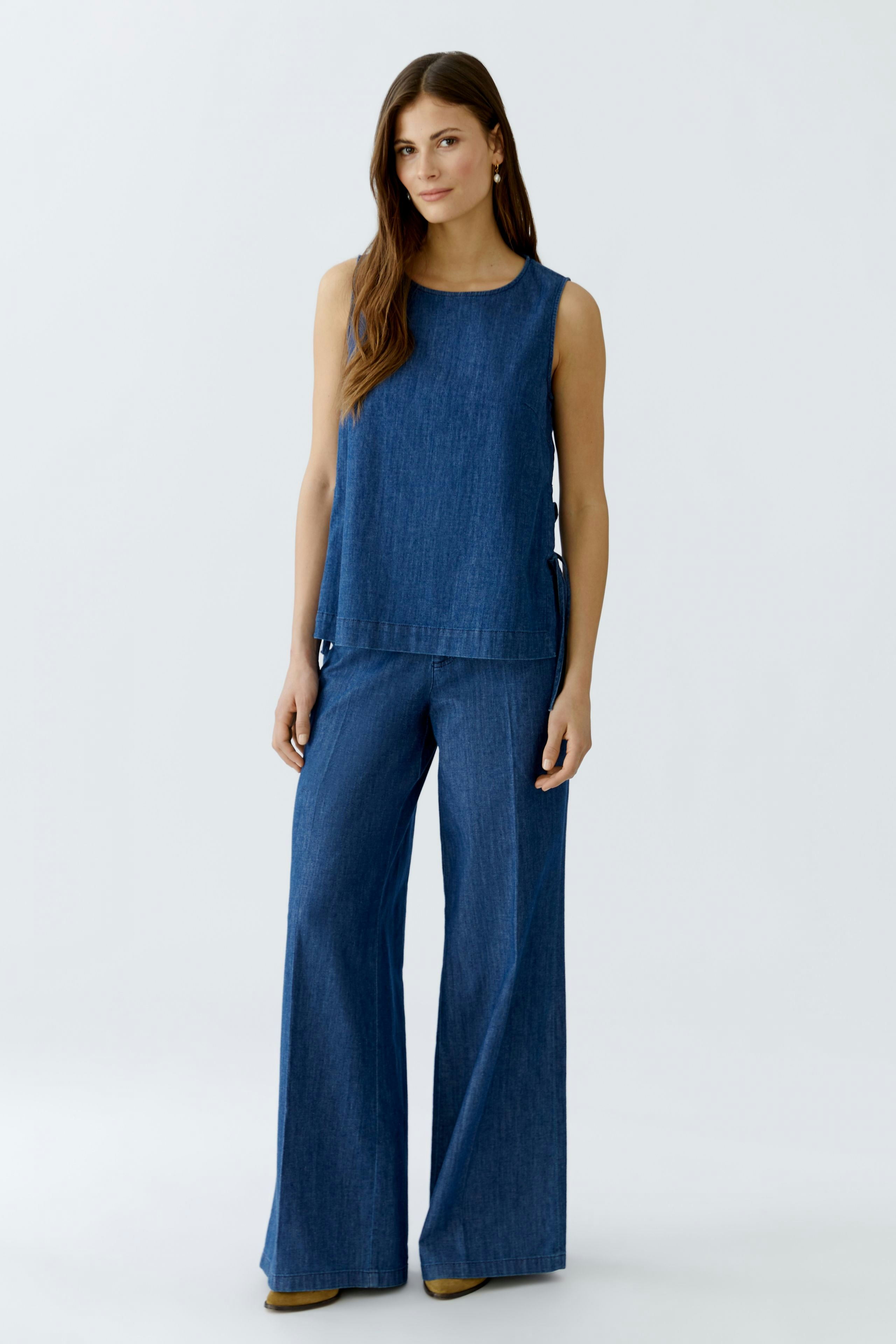Casual women's top: A woman in a blue sleeveless top paired with wide-leg pants, showcasing a relaxed style.