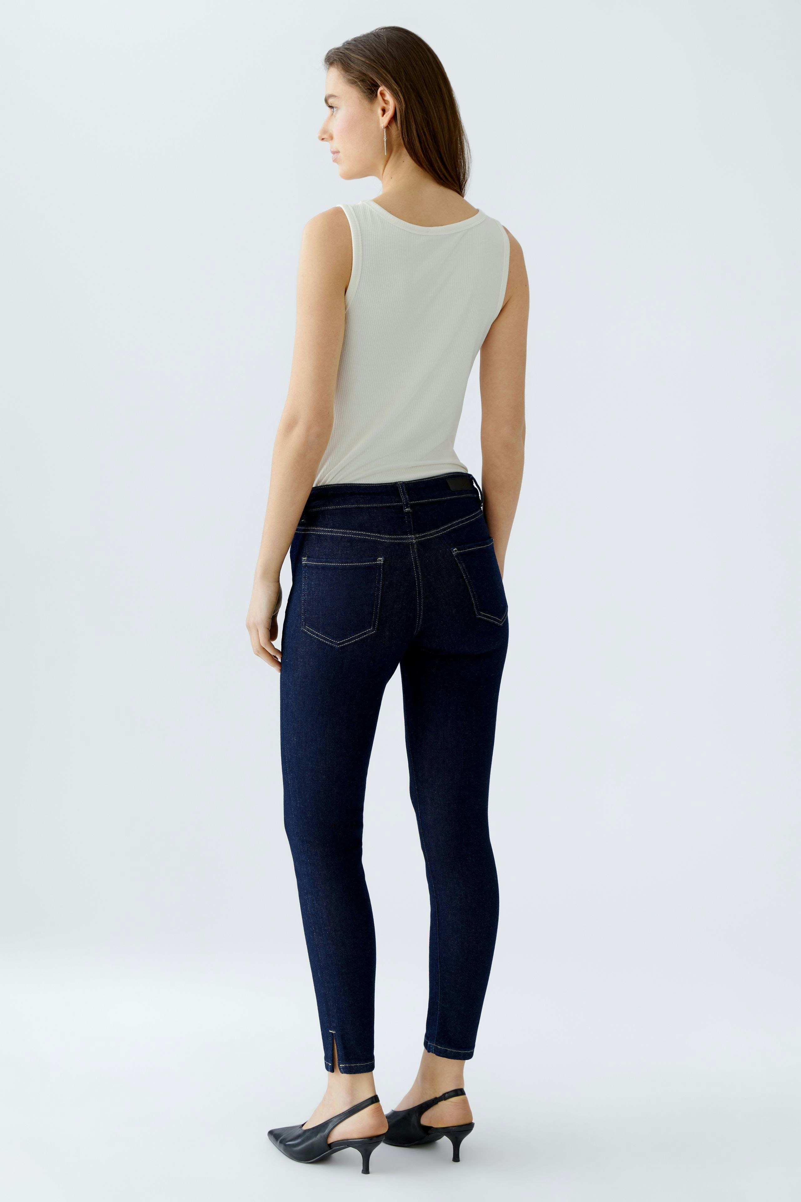 Skinny jeans: Woman in dark blue skinny jeans with a fitted silhouette and stylish ankle detail.