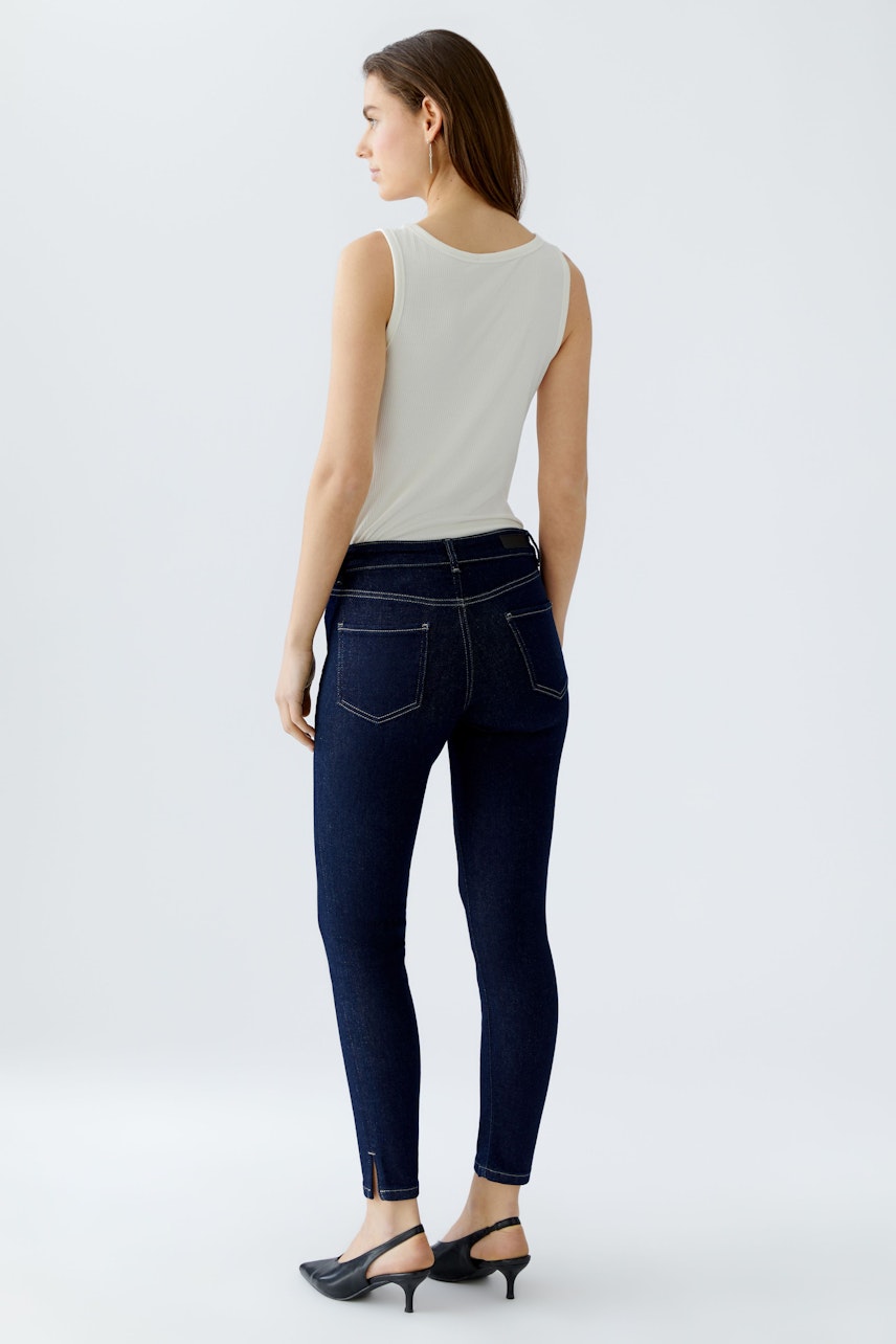 Skinny jeans: Woman in dark blue skinny jeans with a fitted silhouette and stylish ankle detail.