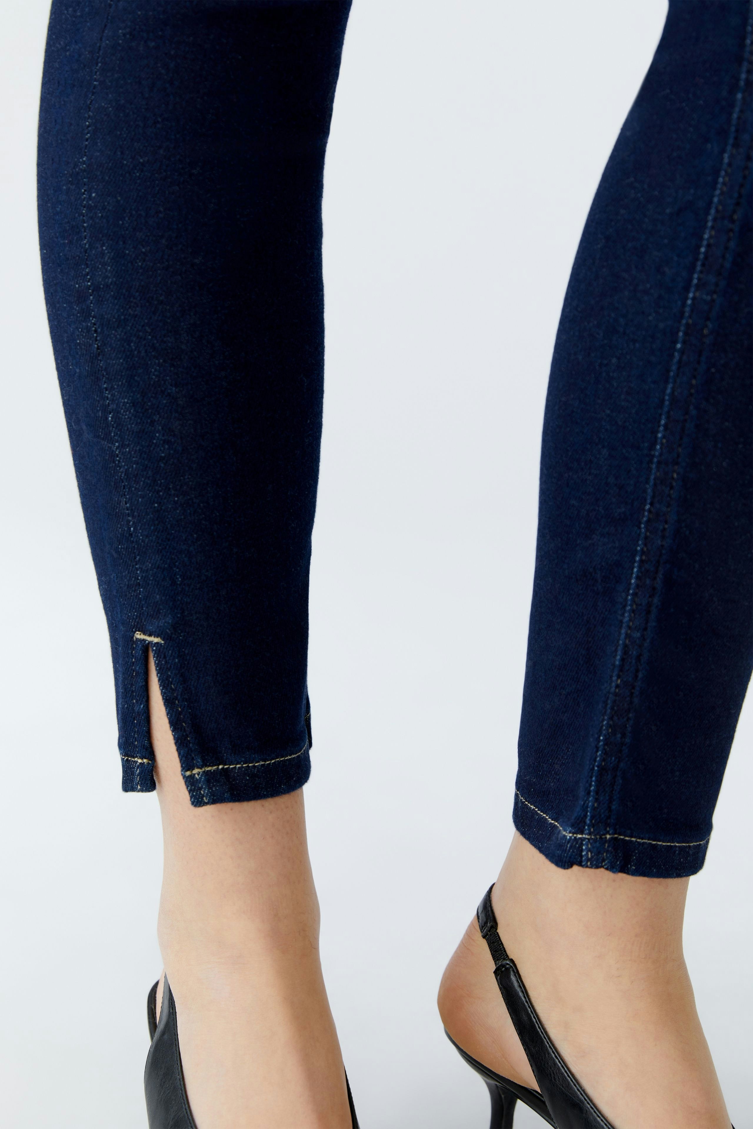 Skinny jeans: Close-up of a woman's legs in dark blue skinny jeans with a stylish slit at the hem.
