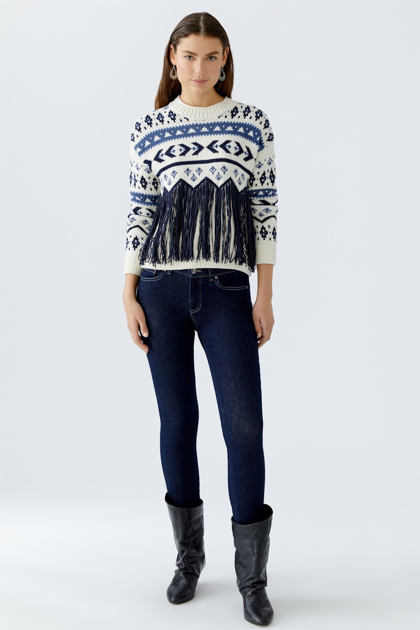 Skinny jeans: Woman in dark blue skinny jeans paired with a stylish fringed pullover.