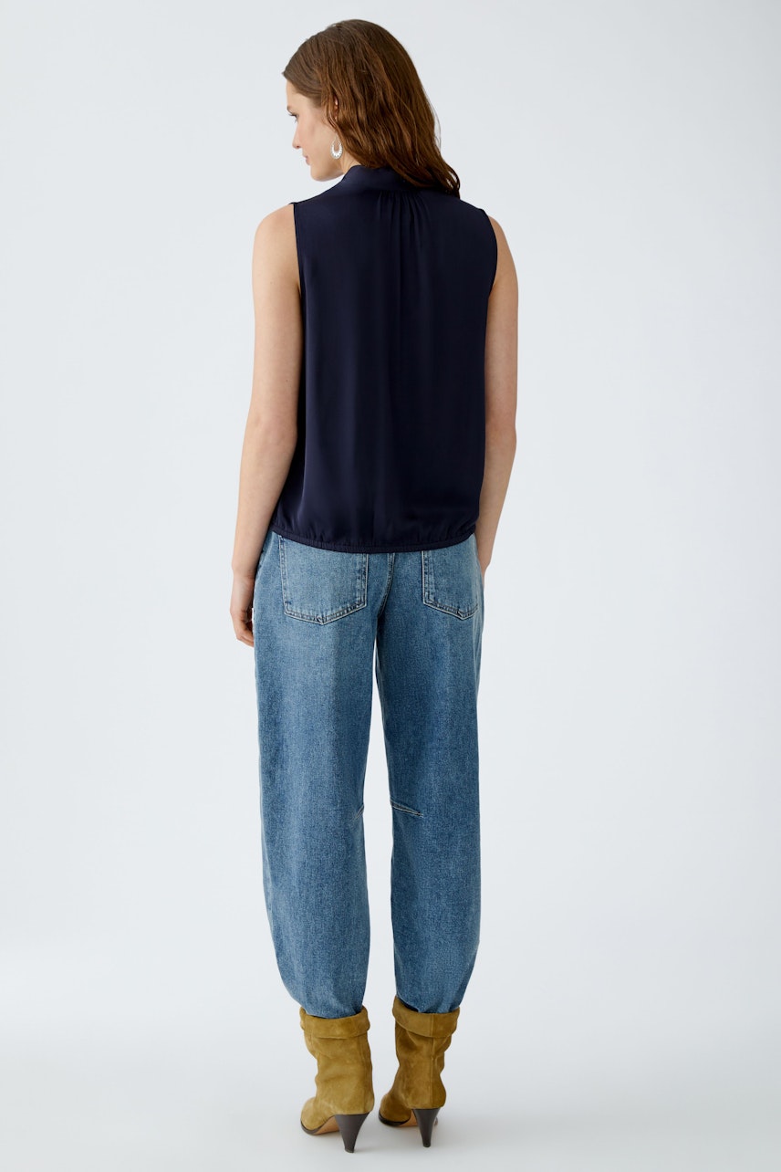 Schluppenbluse: Junge Frau trägt eine navyfarbene Bluse mit Schluppe und lässigen Jeans.