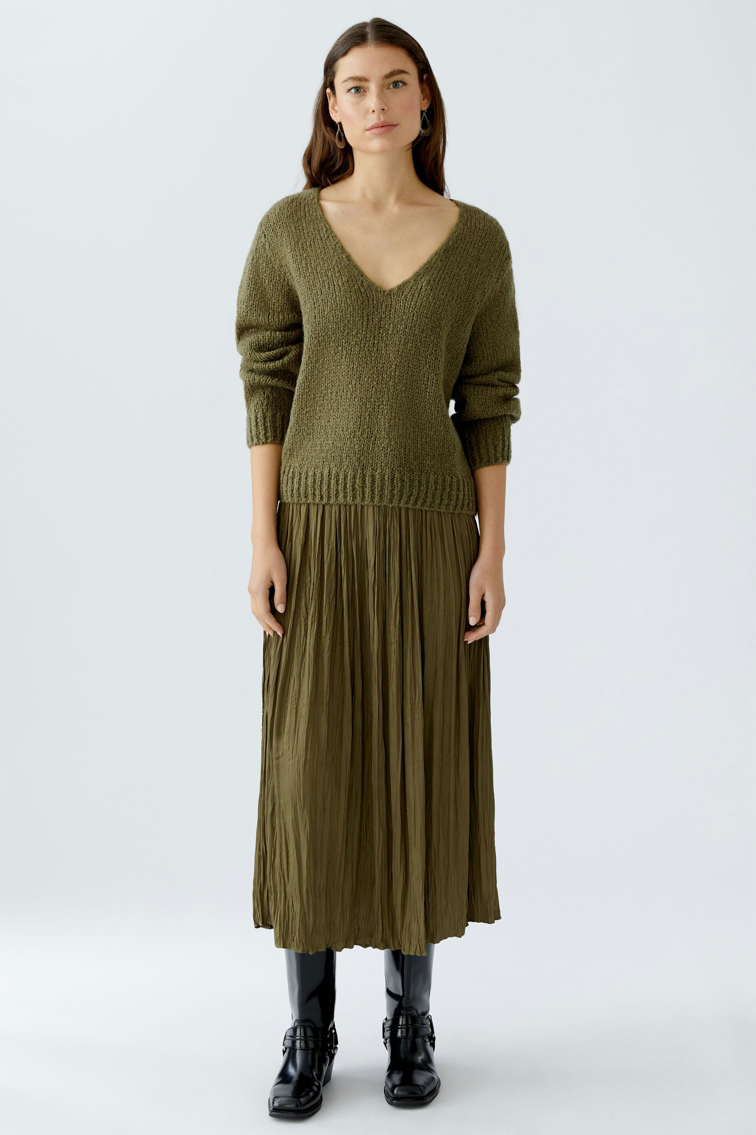 Maxirock in Olivgrün: Frau trägt einen fließenden Maxirock mit V-Ausschnitt und lässigem Strickpullover.