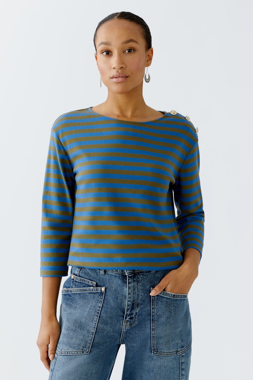 Casual women's long-sleeve shirt: Woman in a blue and green striped pullover with button details.