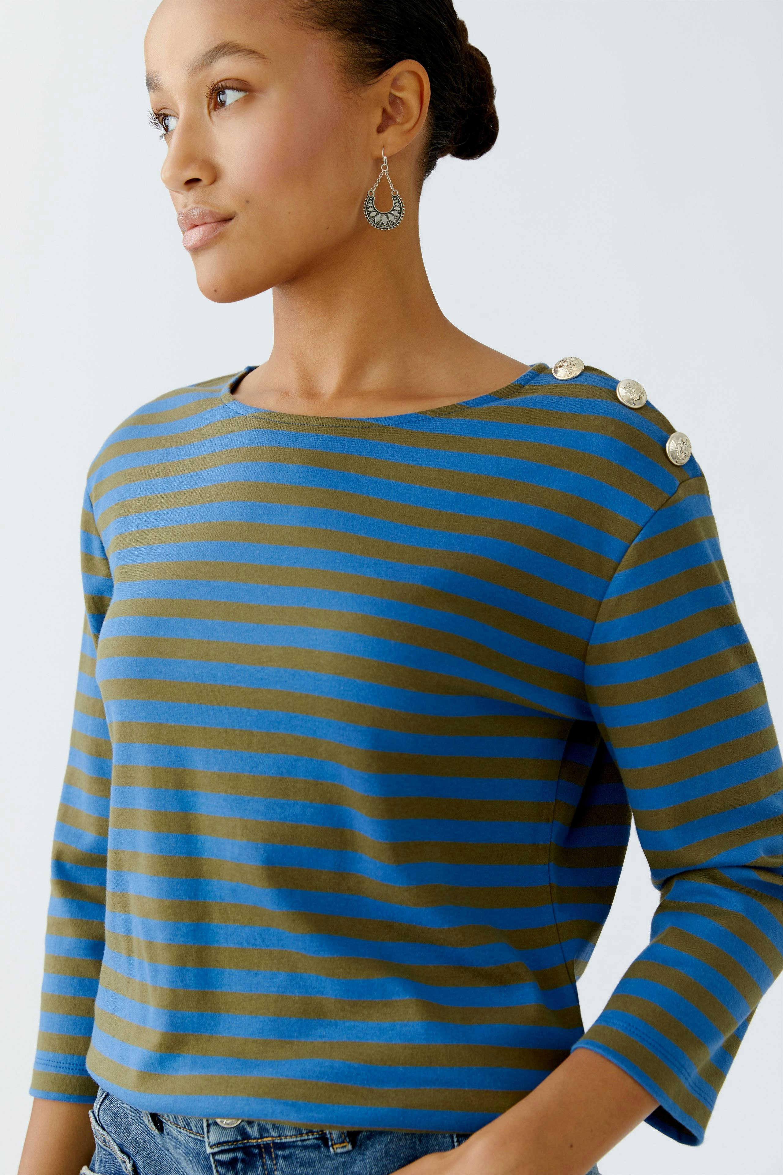 Damen Langarmshirt: Frau trägt ein gestreiftes Shirt in Blau und Braun mit Knöpfen an der Schulter.