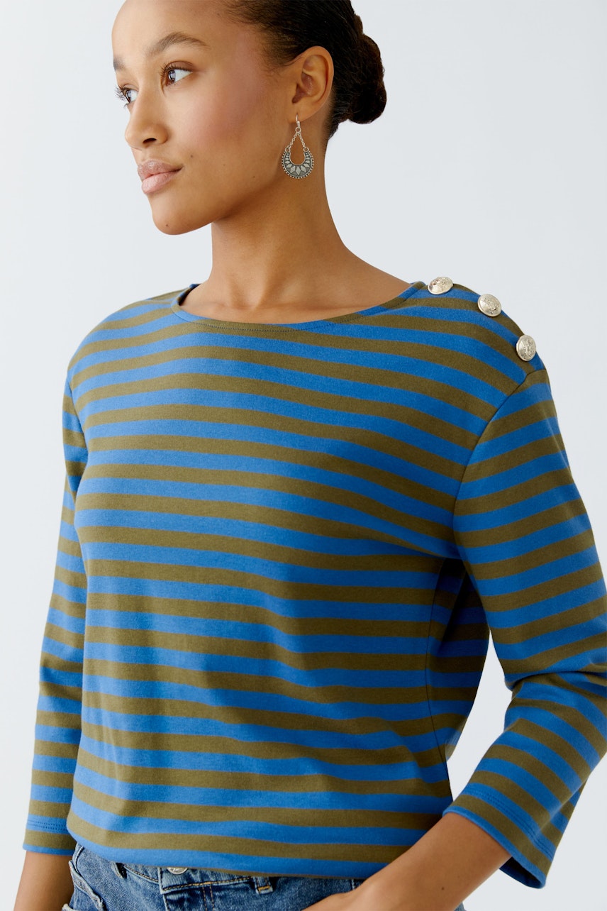 Casual long-sleeve shirt: Woman in a striped pullover with button details, looking stylish and relaxed.