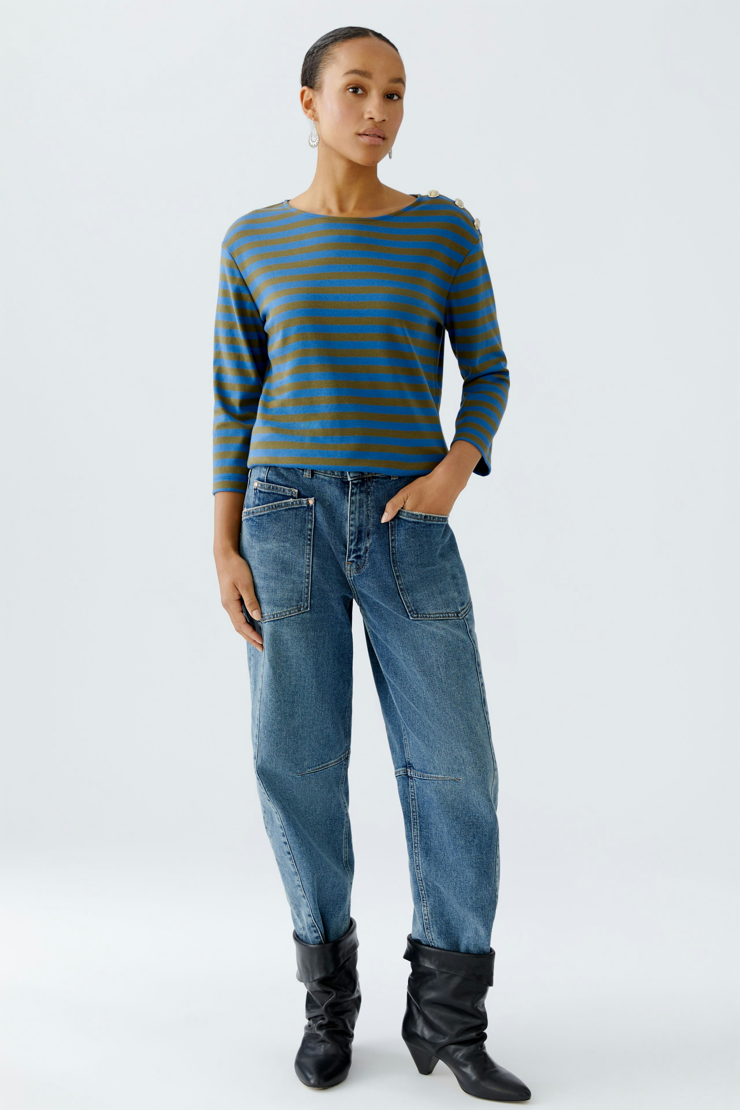 Damen Langarmshirt: Frau in gestreiftem Shirt mit lässigen Jeans und Stiefeln steht entspannt.