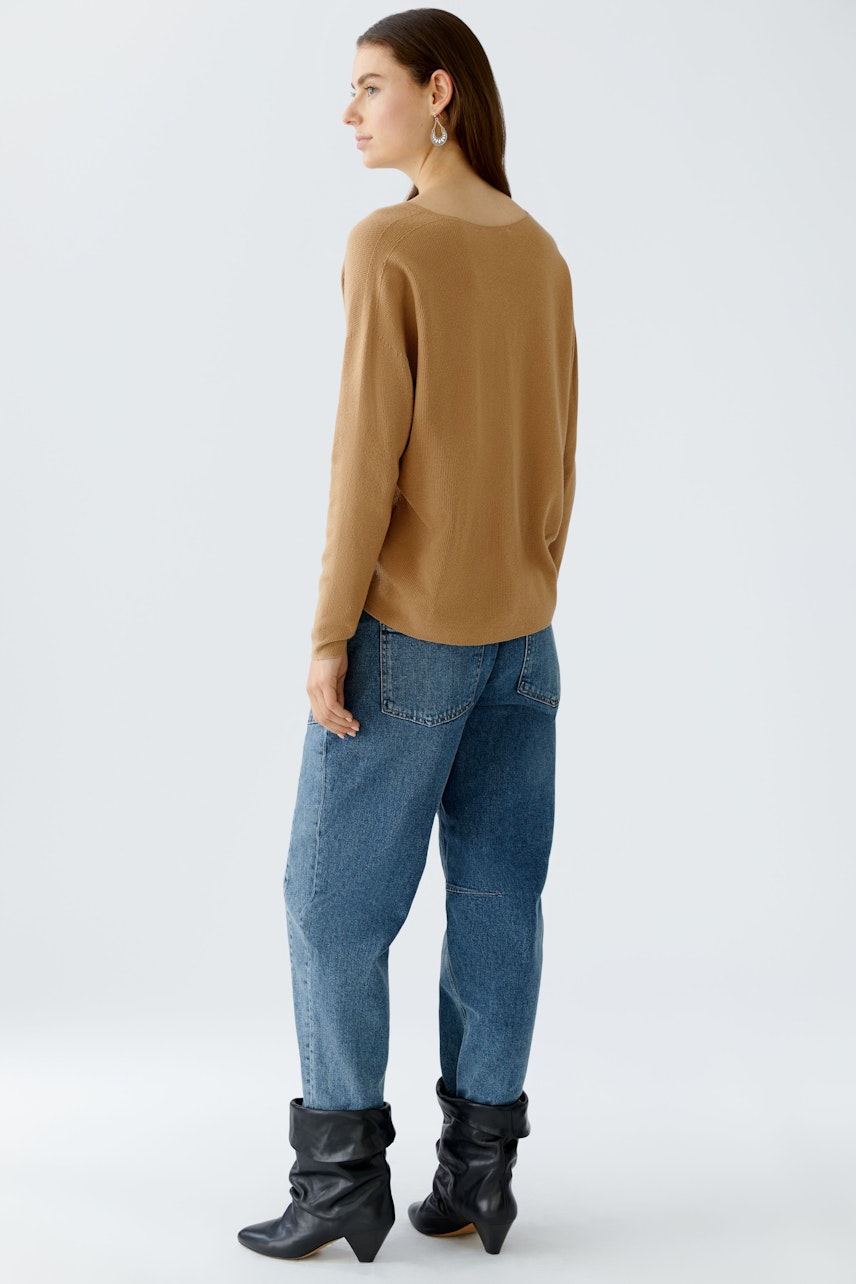 Casual women's pullover: A woman in a brown pullover paired with blue jeans, showcasing a relaxed style.