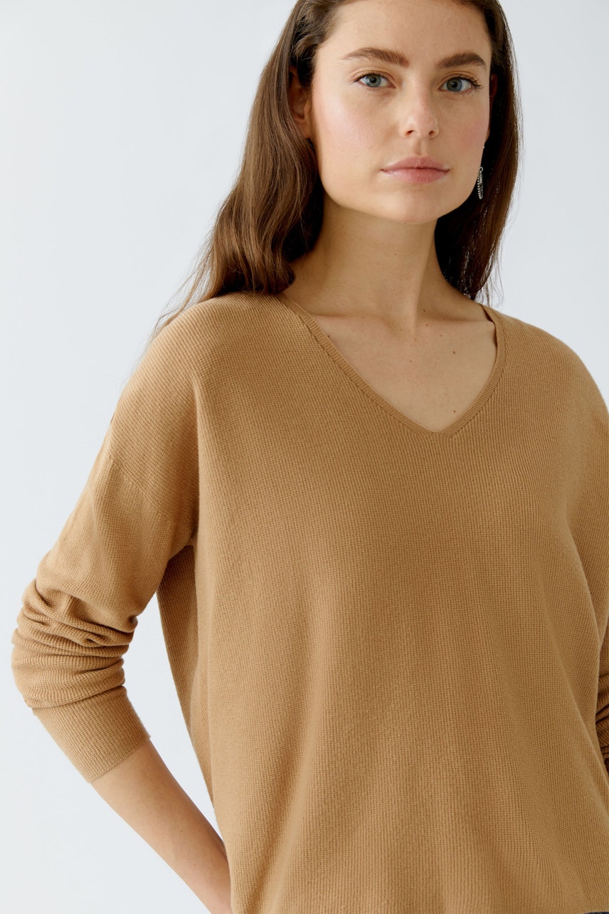 Casual women's pullover: A woman in a light brown V-neck pullover with long sleeves.
