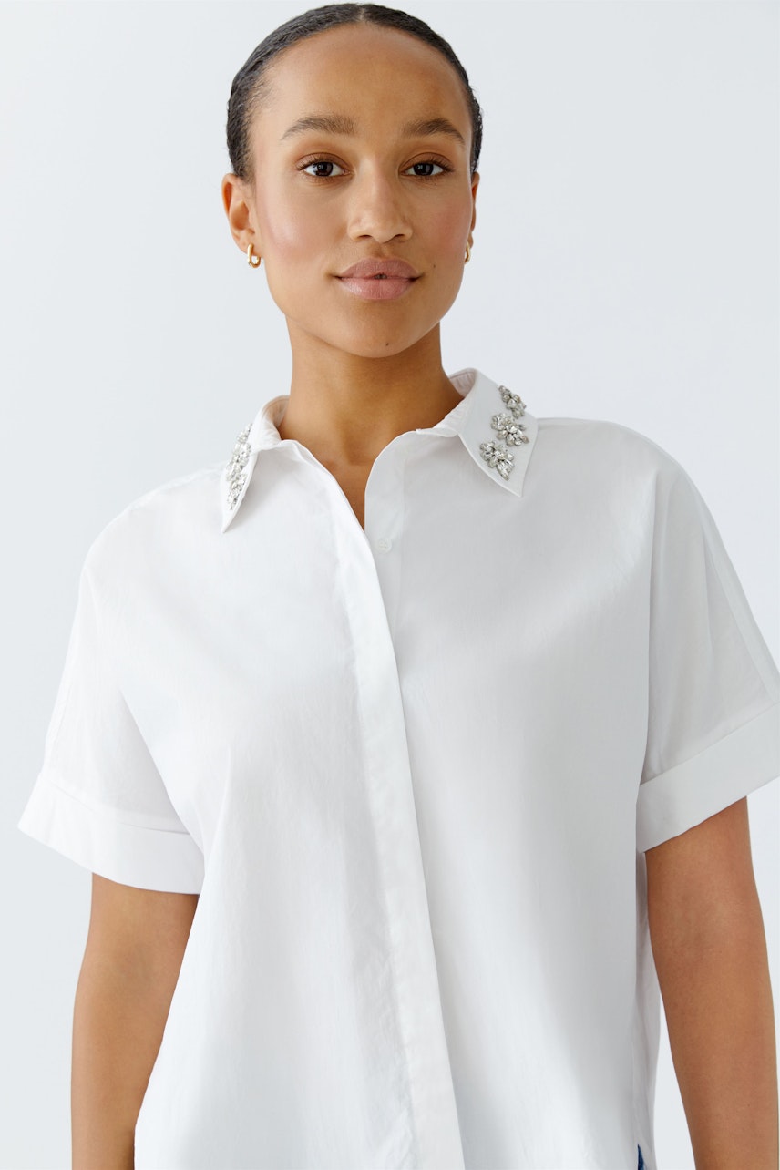 Casual women's blouse: A woman in a white shirt with embellished collar, exuding a relaxed vibe.