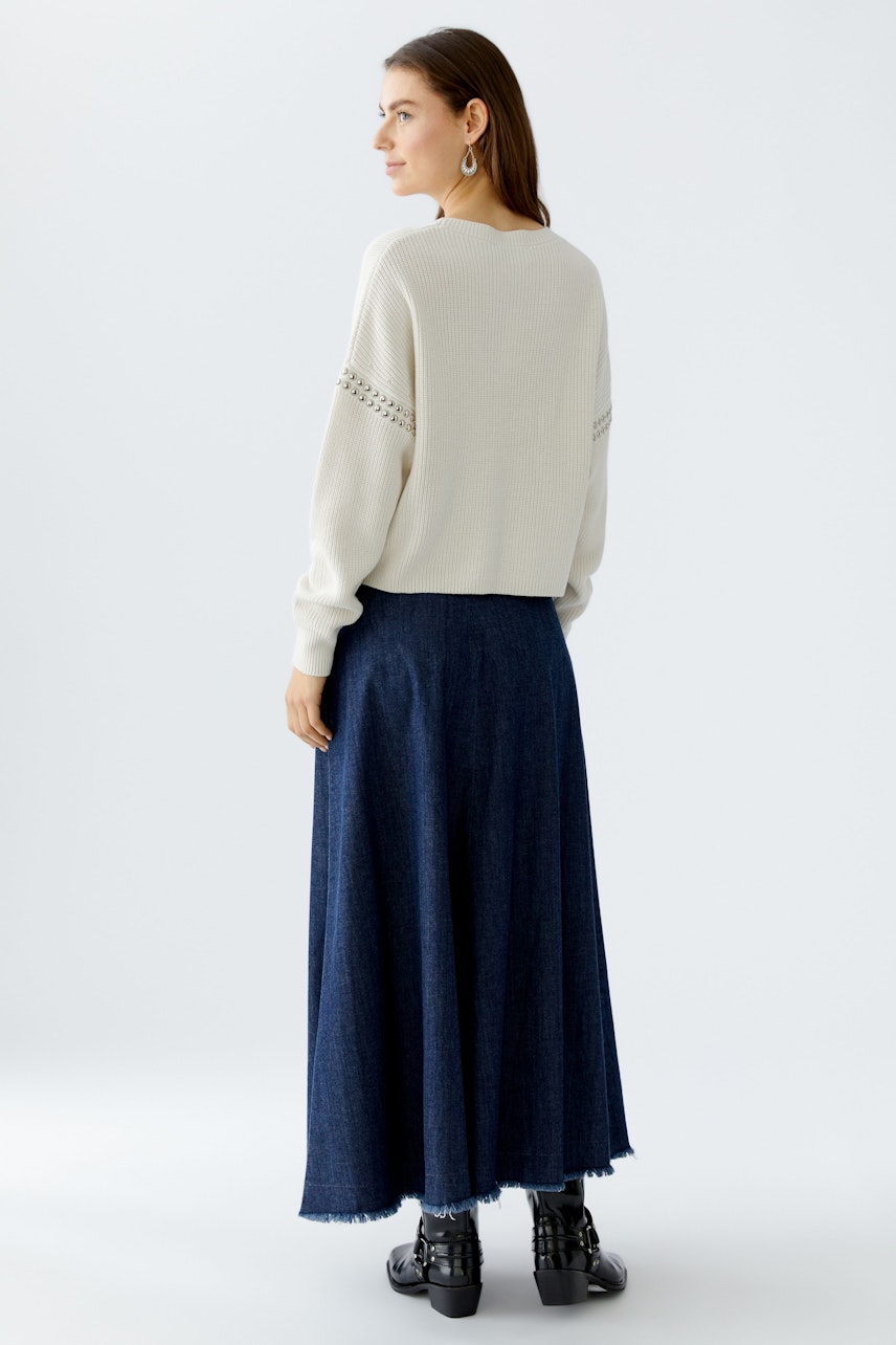 Casual women's pullover: A woman in a light pullover with a relaxed fit, paired with a long denim skirt.
