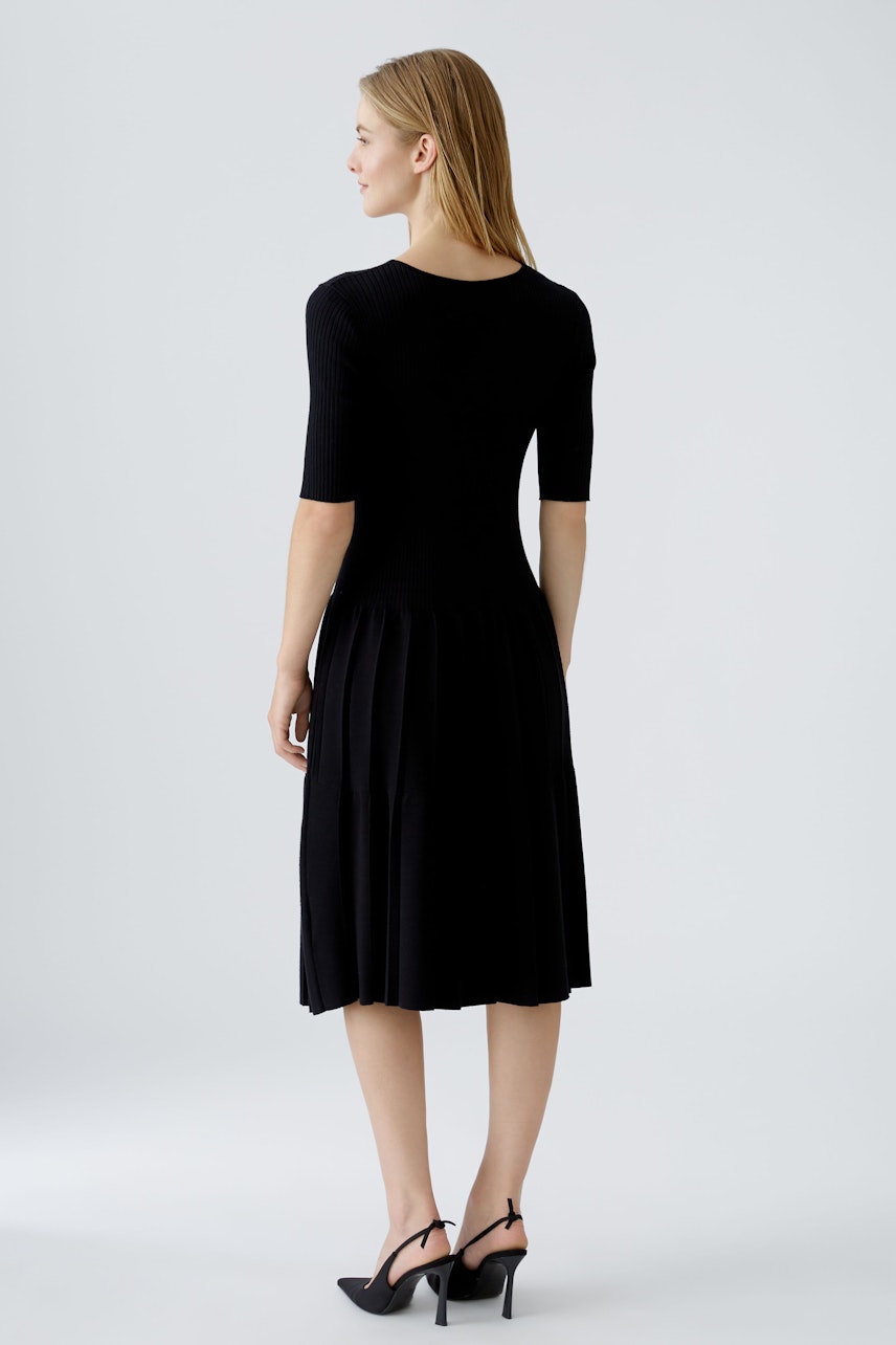 Schwarzes Strickkleid: Frau mit kurzem Armkleid, das locker fällt und eine moderne Silhouette bietet.