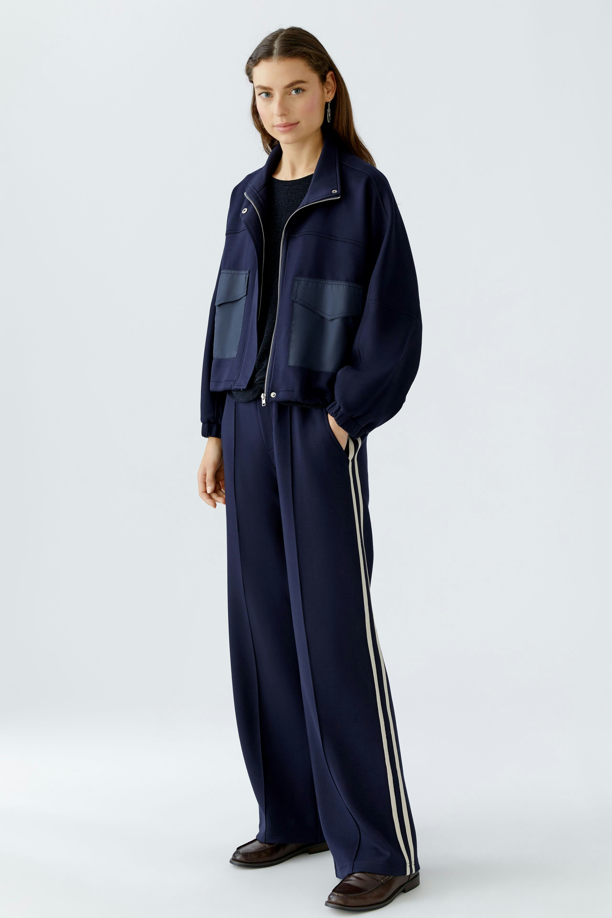 Bequeme Damen-Jogger: Frau in navy Jogginghose mit seitlichen Streifen und lässiger Jacke.
