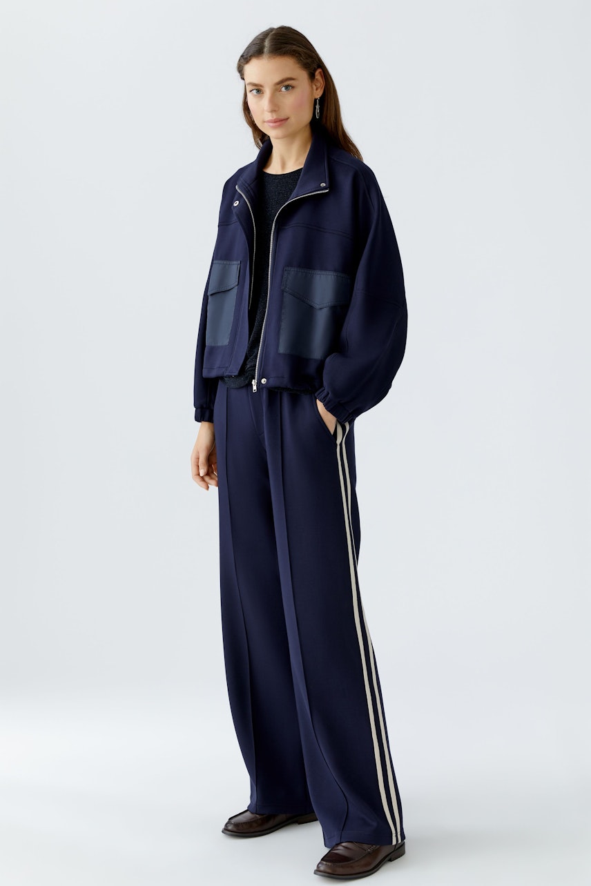 Casual women's joggers: A woman in navy joggers with side stripes and a matching jacket stands confidently.