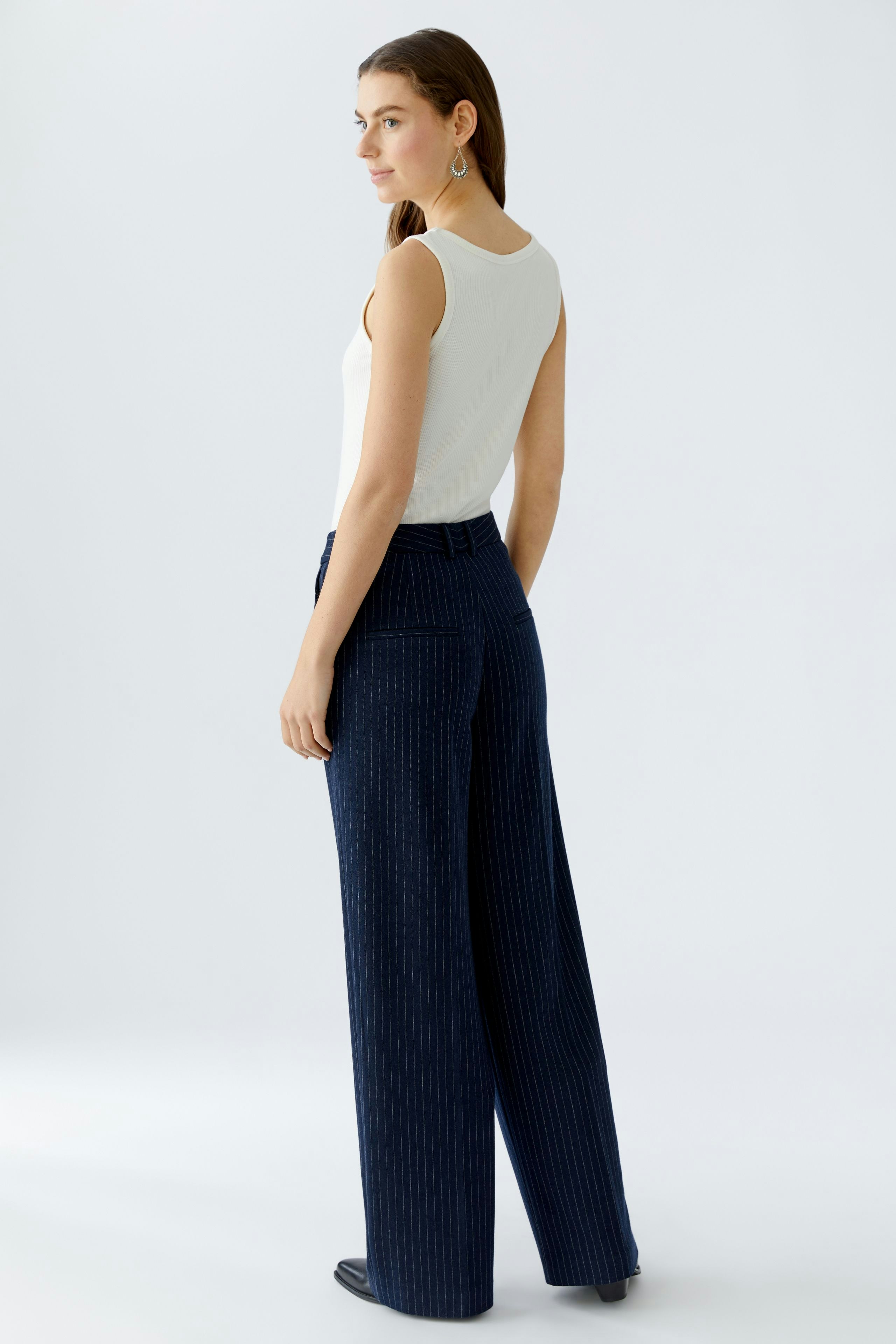 Wide-leg trousers: Woman in navy pinstriped trousers, showcasing a relaxed fit and modern style.