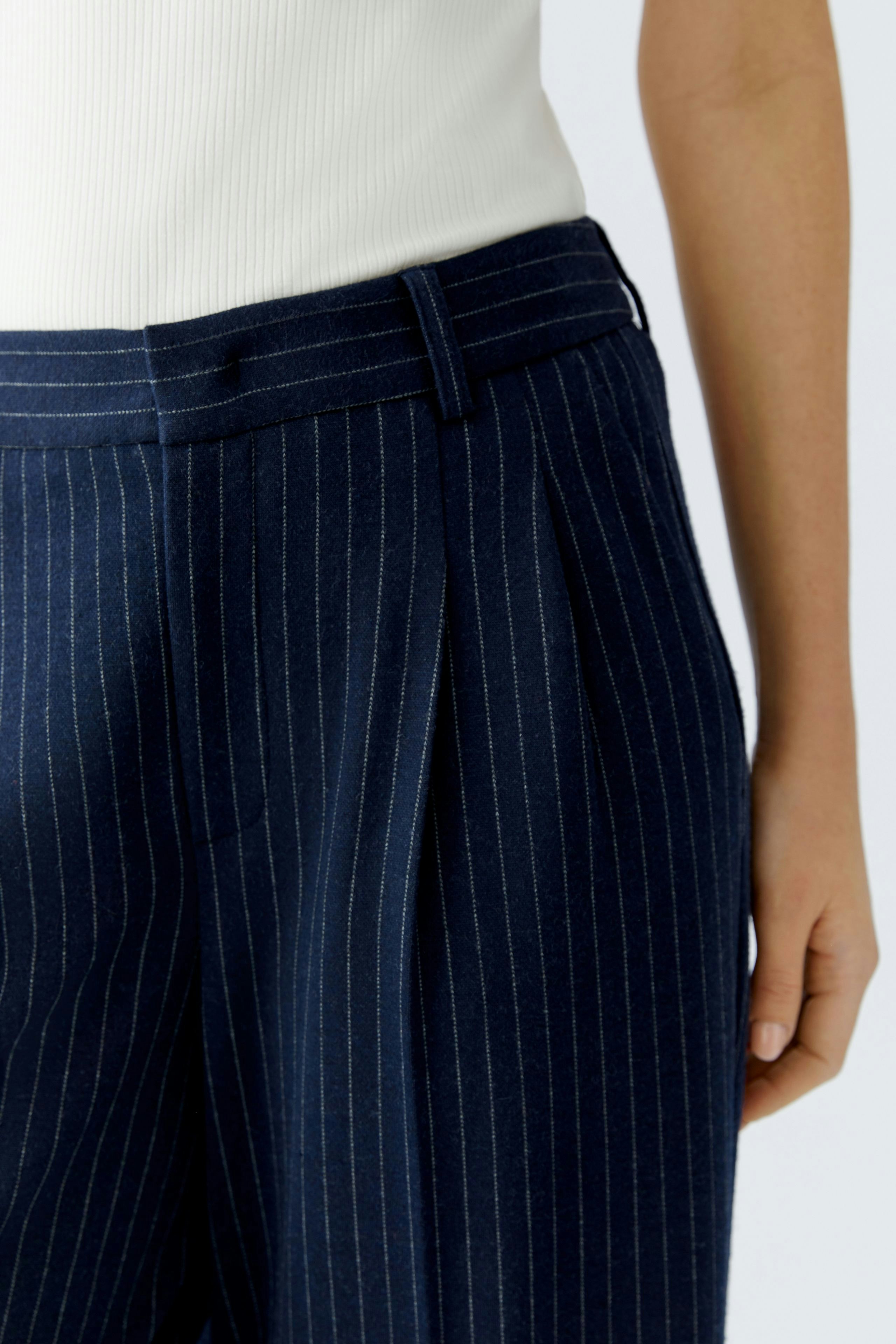 Stylish women's pleated trousers in navy with pinstripes, paired with a fitted top.