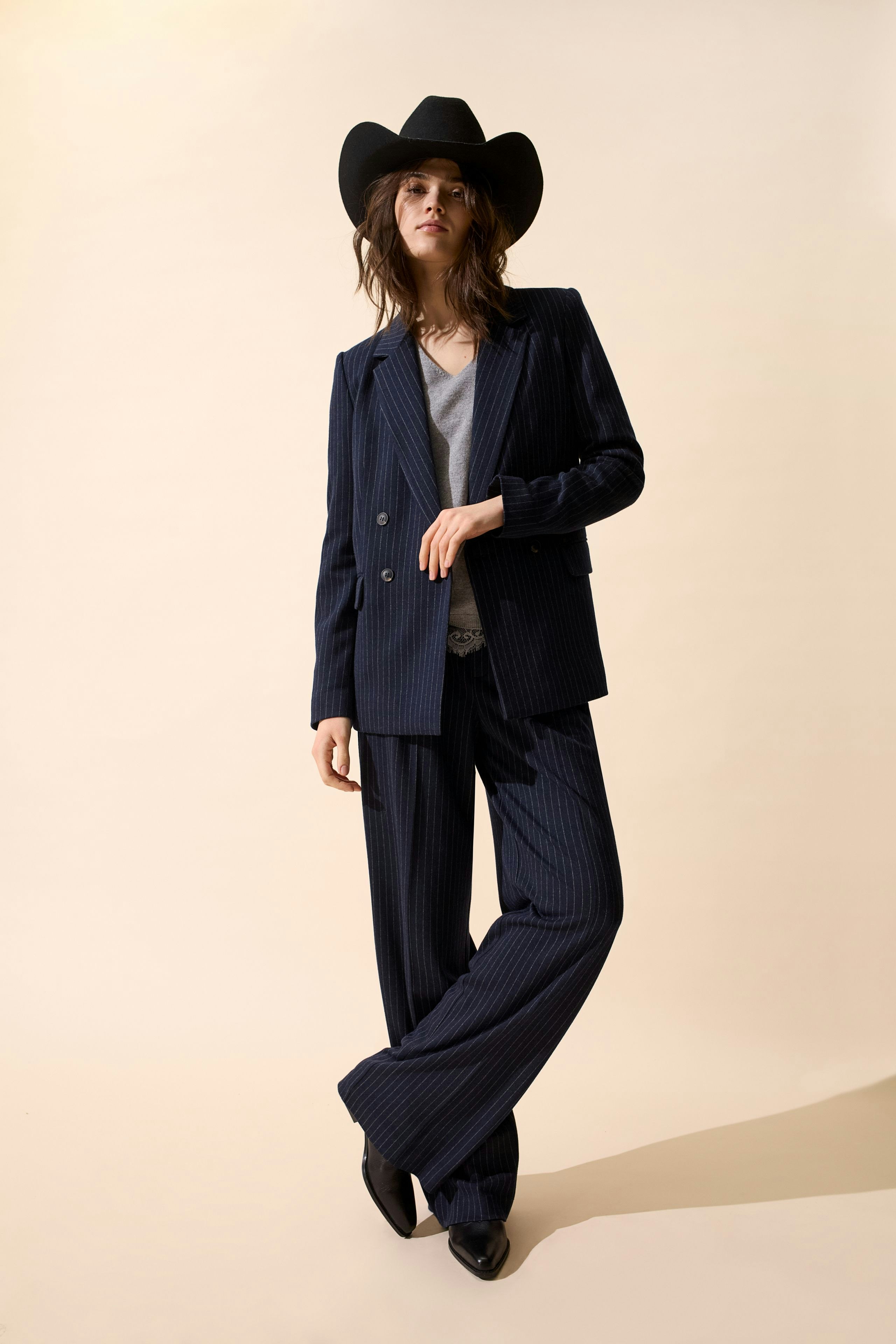 Stylish women's pleated trousers: A woman in navy pinstripe pants and a matching blazer.
