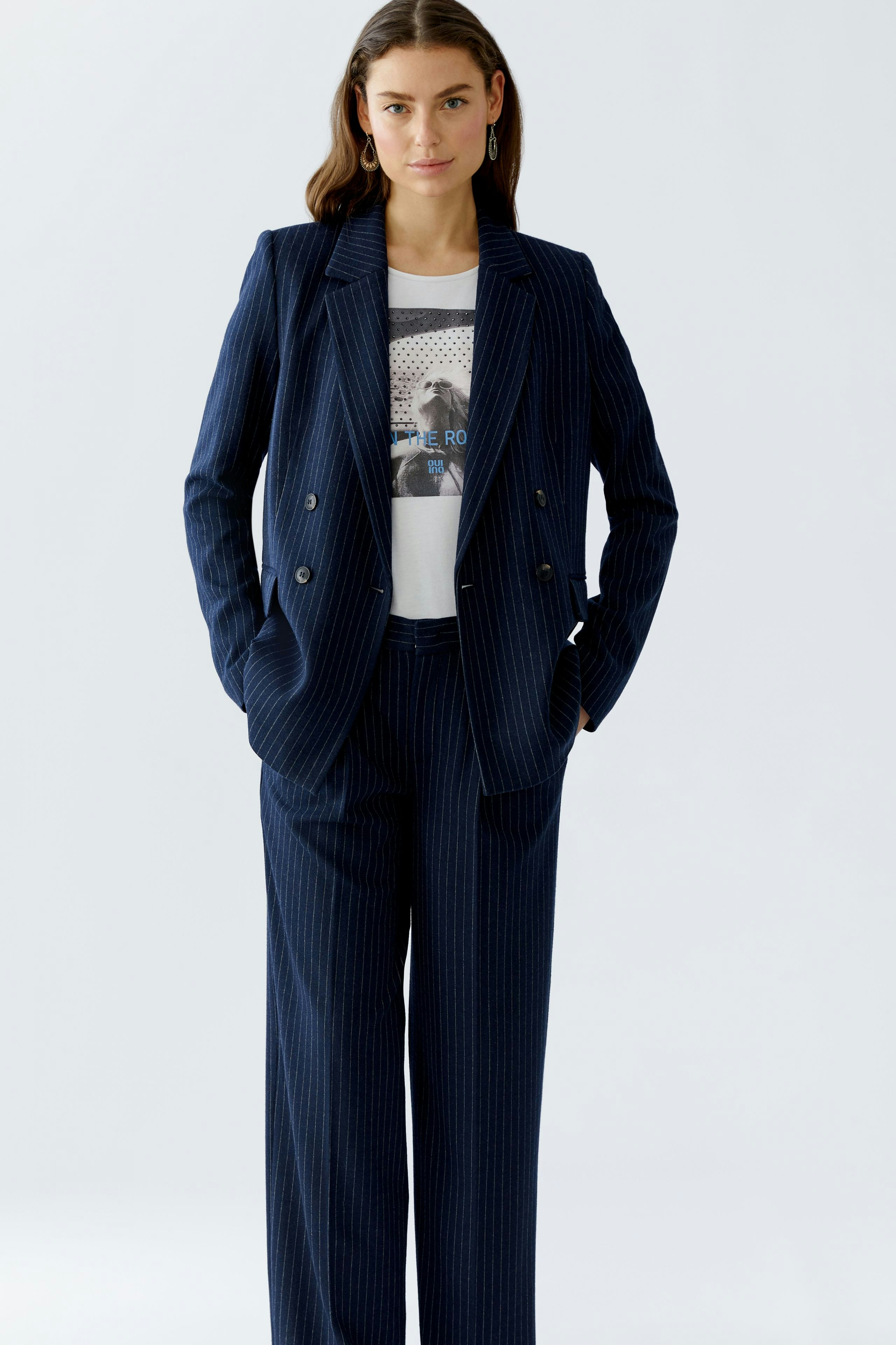 Stylish women's pleated trousers paired with a matching blazer and graphic tee, showcasing a modern look.