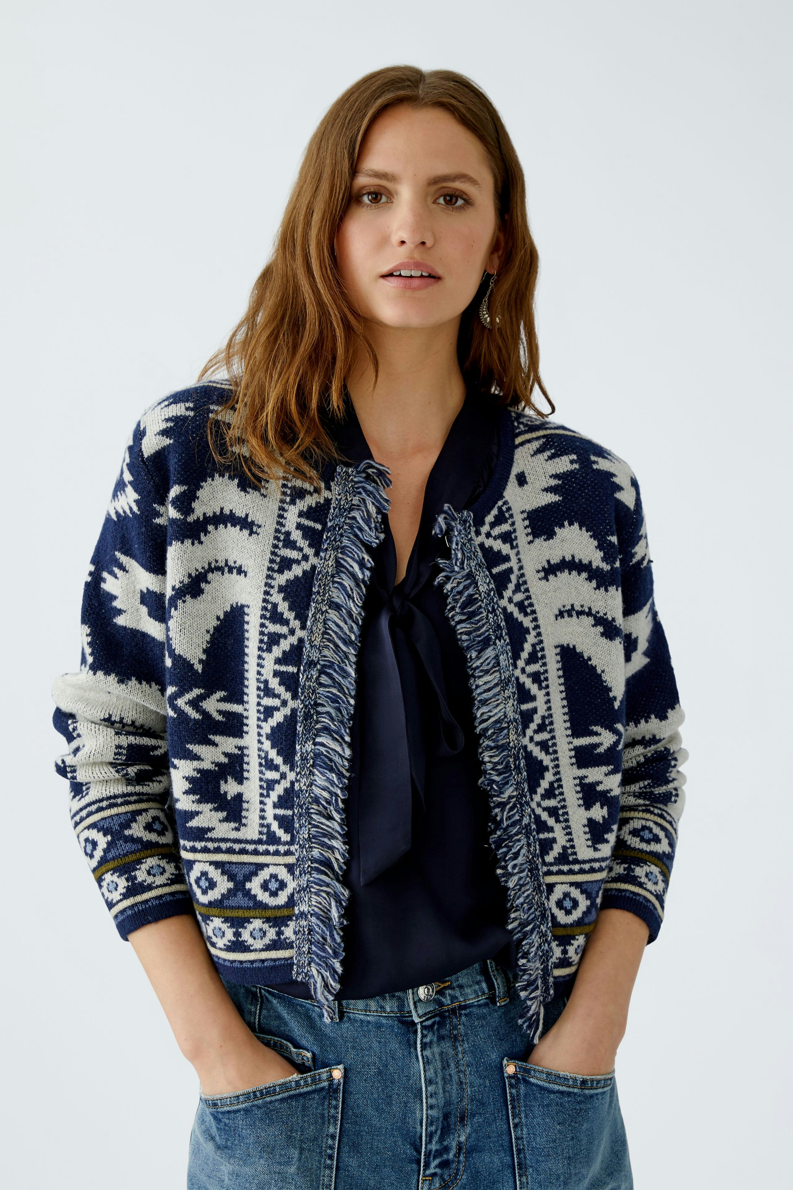 Casual women's cardigan: A woman in a navy patterned cardigan with fringe details, paired with a dark top.
