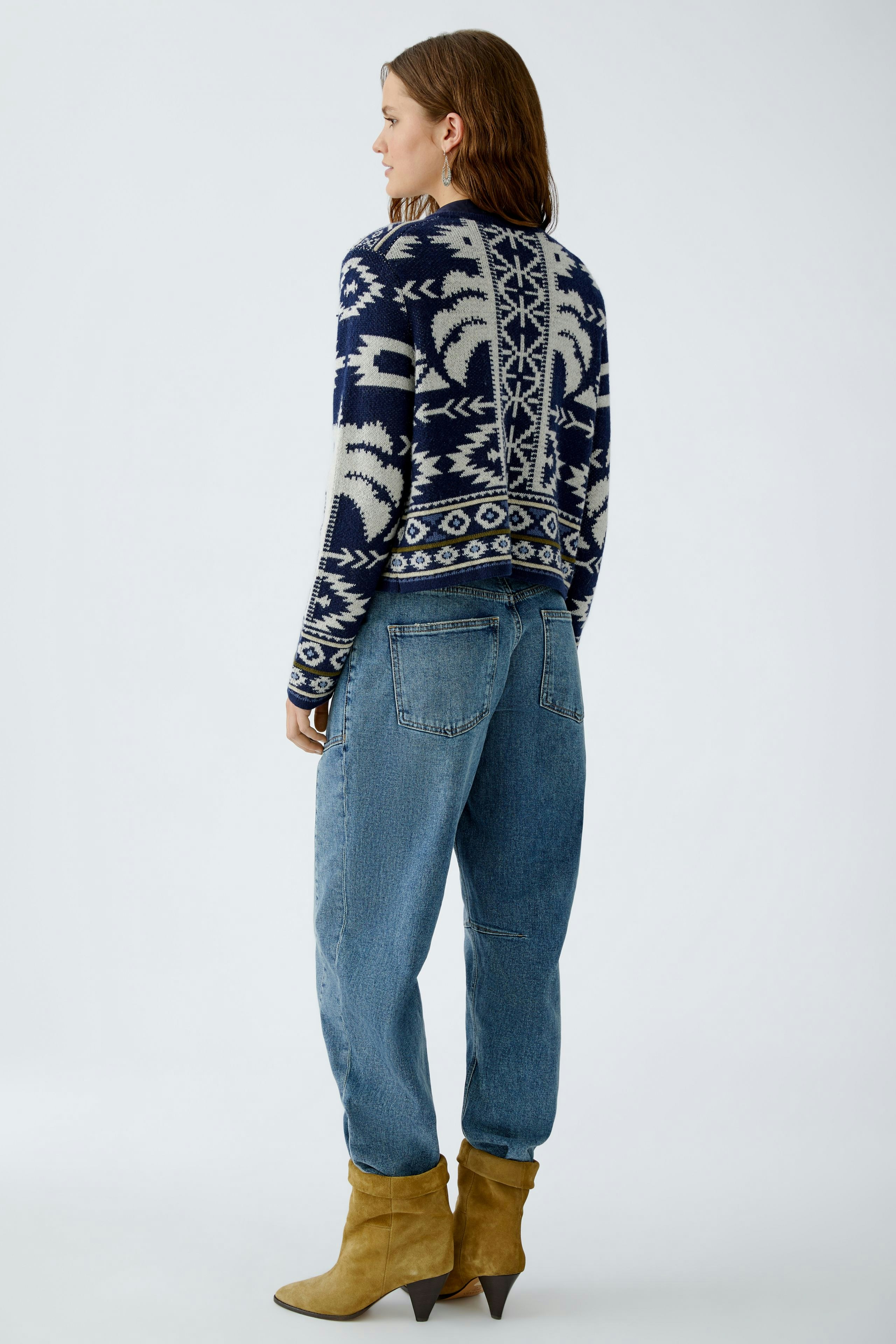 Casual women's cardigan: A woman in a patterned navy cardigan paired with relaxed jeans.