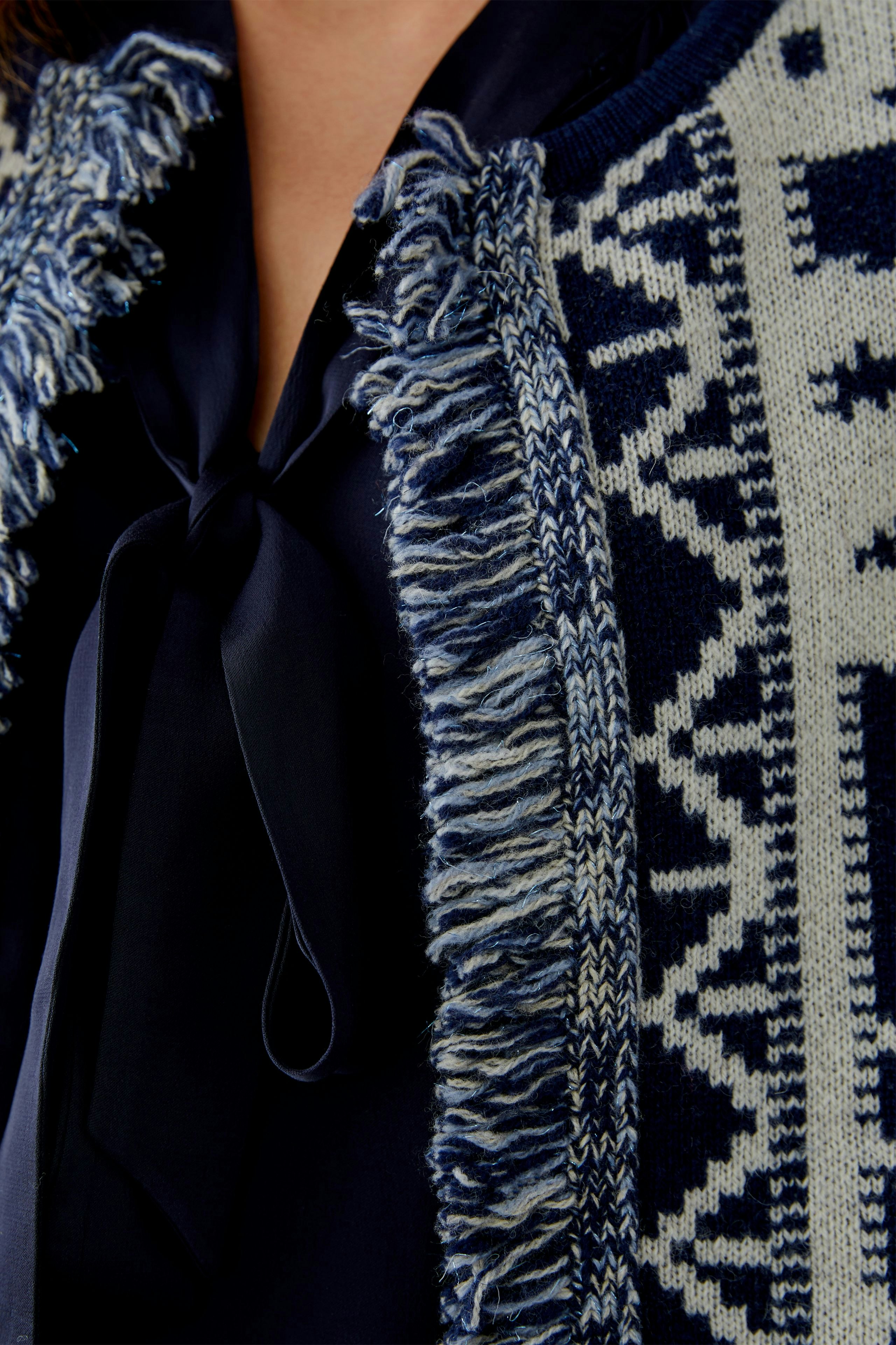 Casual women's cardigan: Close-up of a woman in a navy patterned cardigan with fringes.