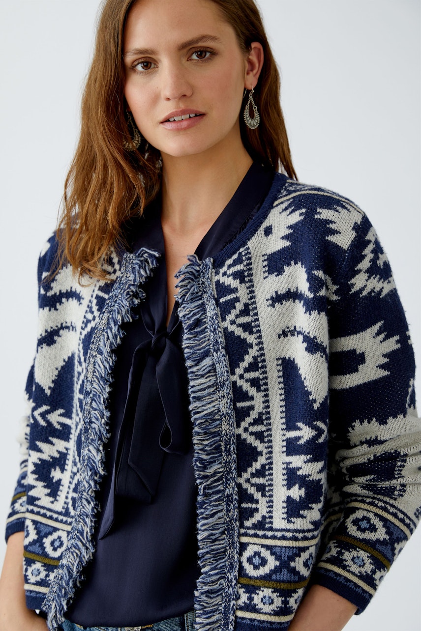 Damen-Strickjacke: Frau trägt eine navyfarbene Strickjacke mit fransigen Details und grafischem Muster.