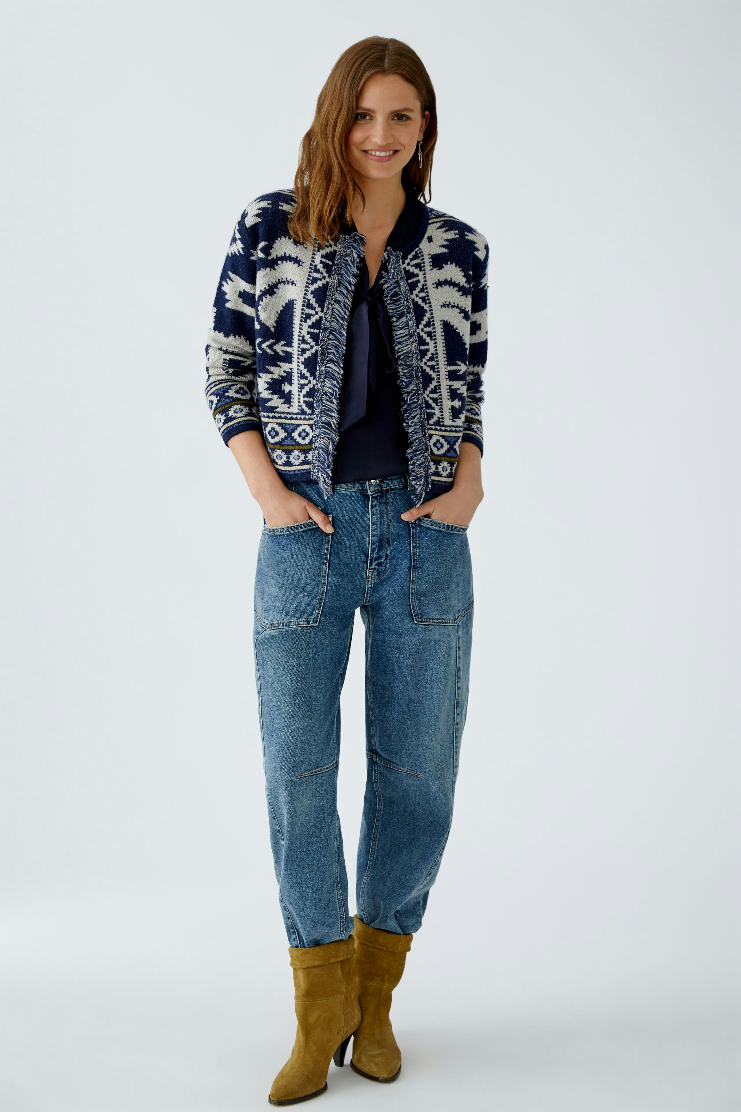 Casual women's cardigan: Smiling woman in a navy patterned cardigan over a top and relaxed jeans.