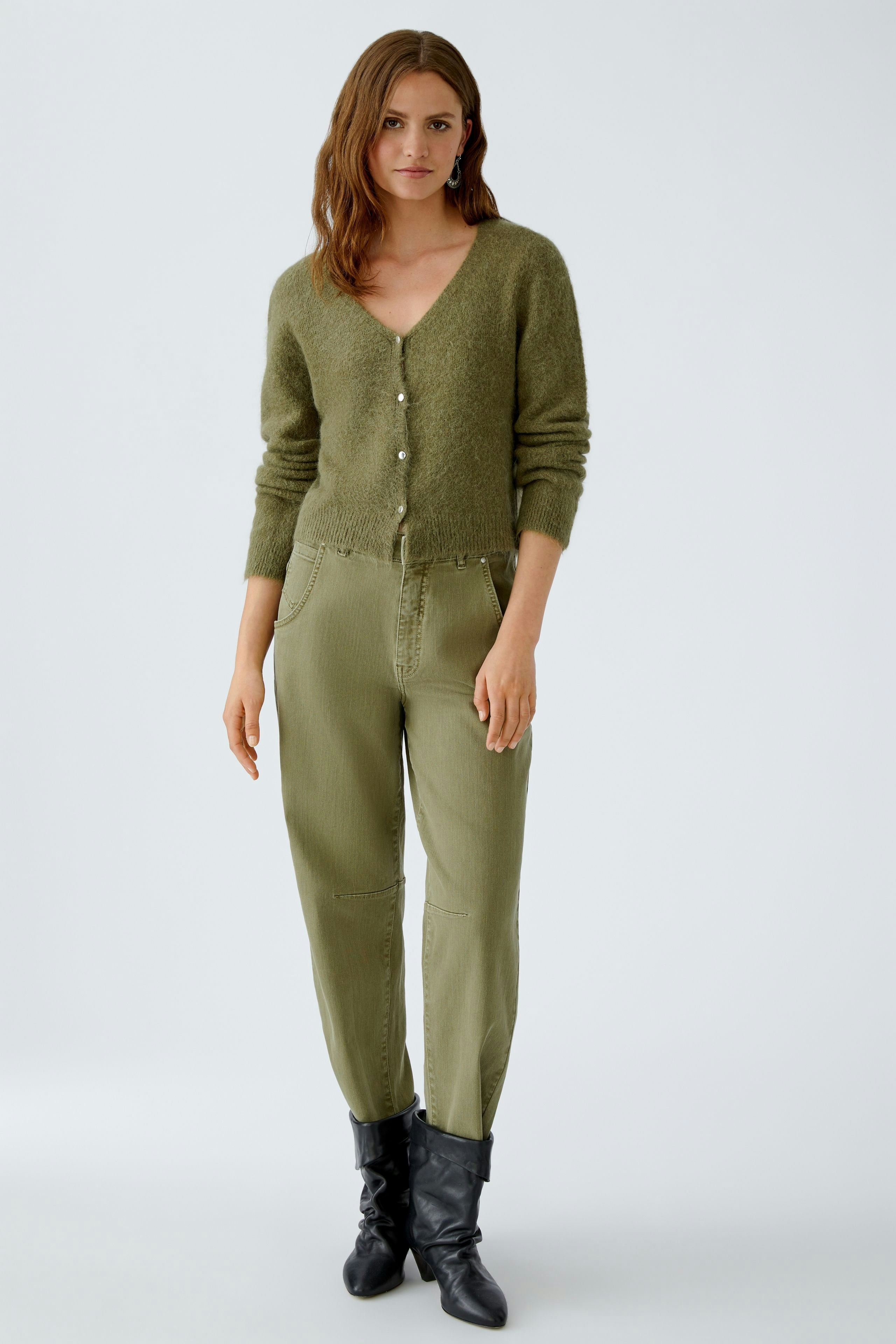 Damen-Strickjacke: Frau in olivgrüner Strickjacke mit Knöpfen und lässigen Hosen.