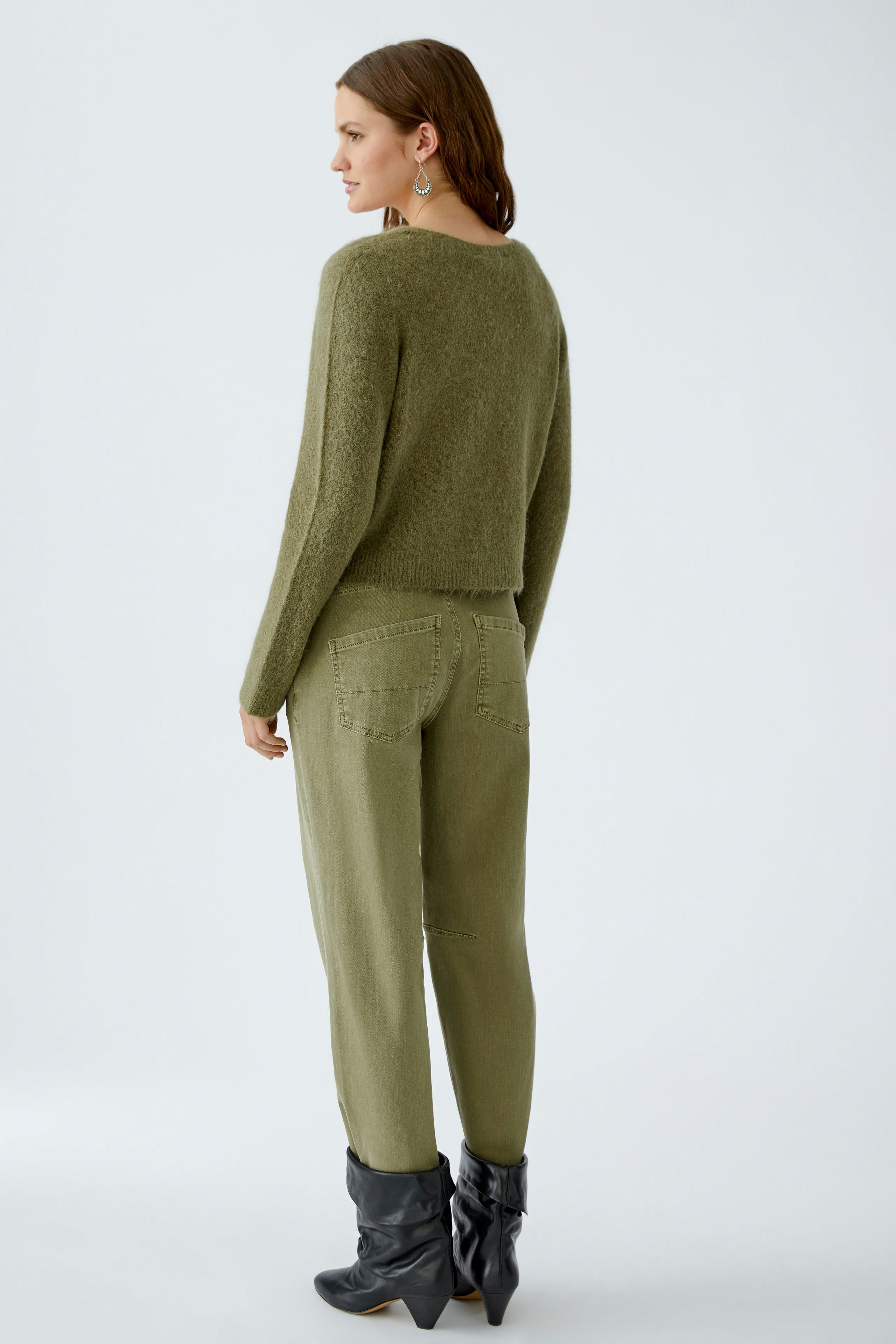 Damen-Strickjacke: Frau in olivgrüner Strickjacke mit lässigem Schnitt und bequemen Hosen.