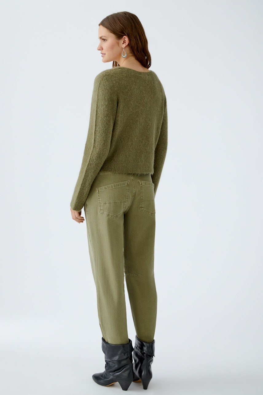 Damen-Strickjacke: Frau in olivgrüner Strickjacke mit lässigem Schnitt und bequemen Hosen.