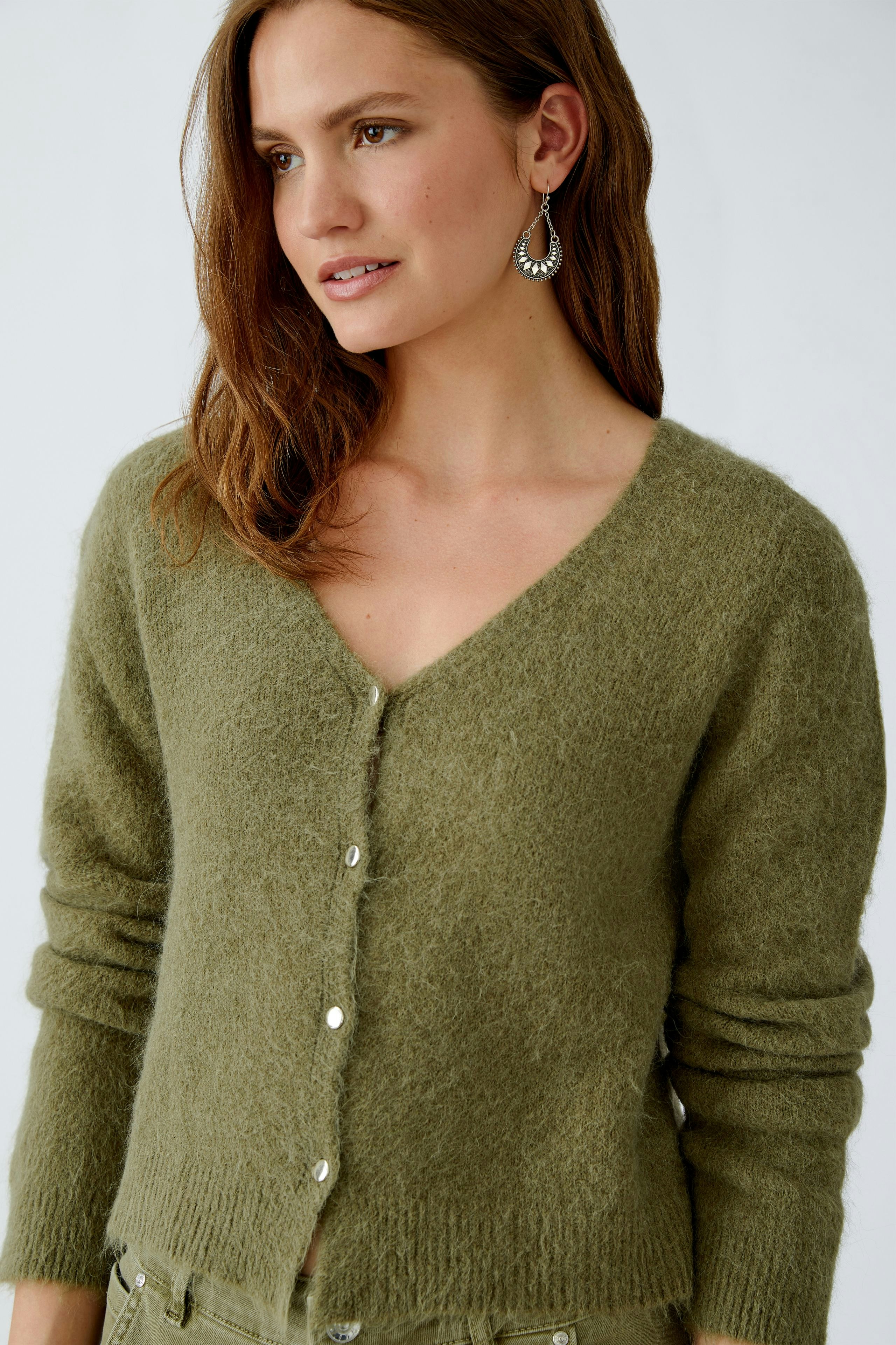 Damen-Strickjacke: Frau in olivgrüner Strickjacke mit Knöpfen, lässig und bequem.