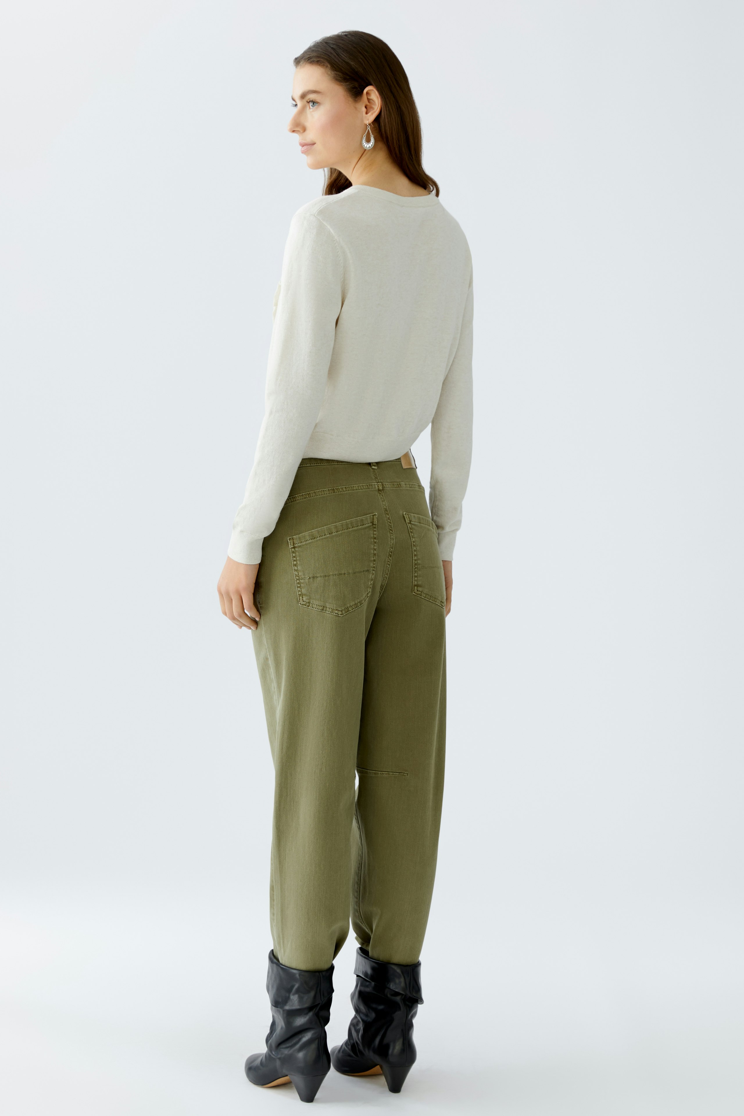 Casual women's cardigan: A woman in a light sweater and olive green pants stands confidently.