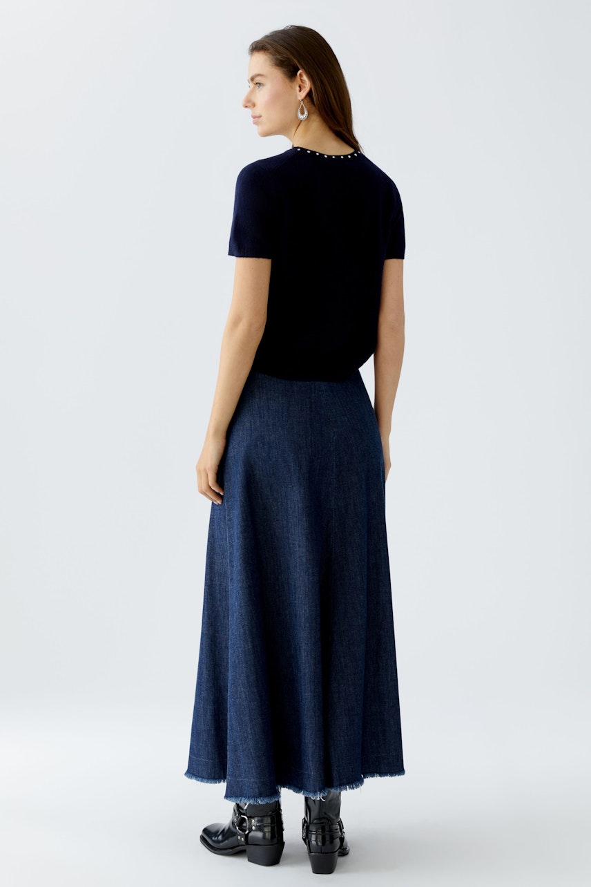 Casual women's pullover: Young woman in a navy pullover paired with a long denim skirt.